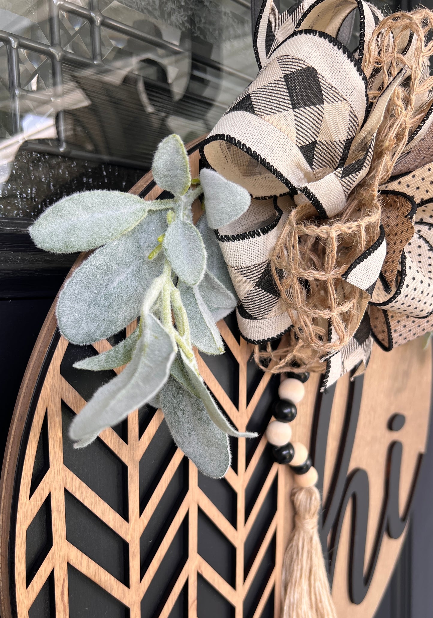 Decorative wreath with plaid ribbon, eucalyptus leaves, and geometric design on a birchwood door hanger.