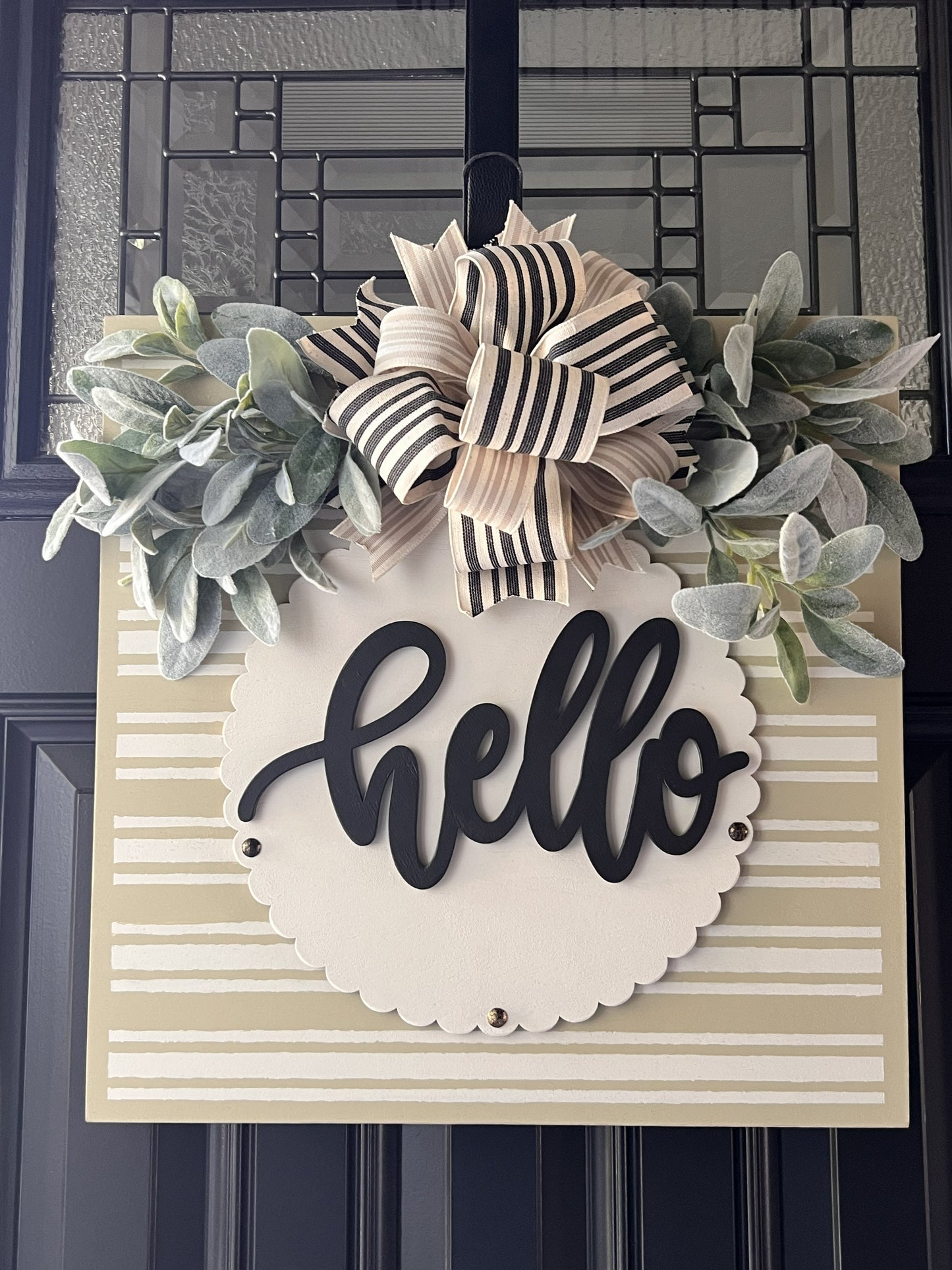 neutral hello door hanger with striped background and greenery bow