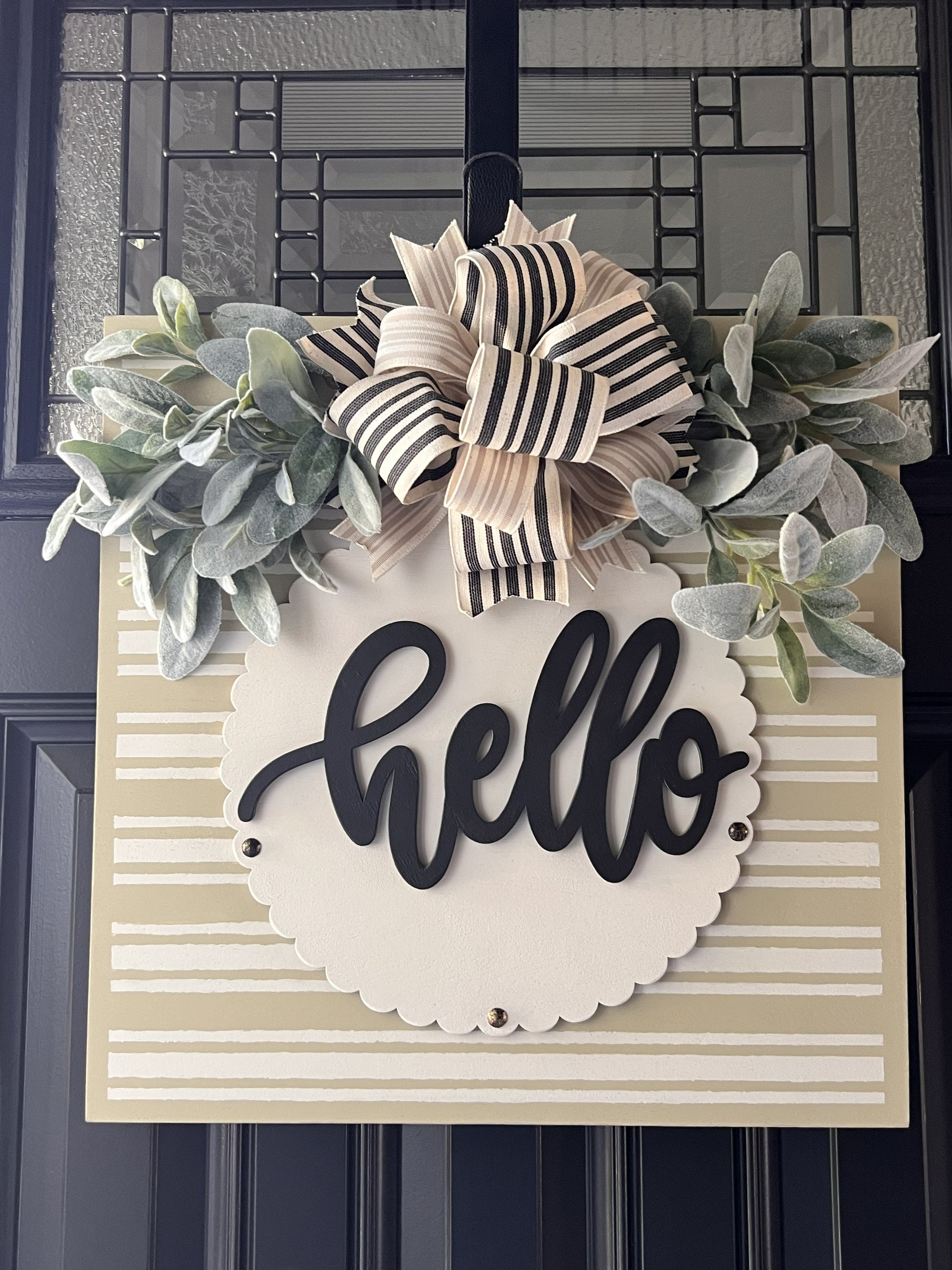neutral hello door hanger with striped background and greenery bow