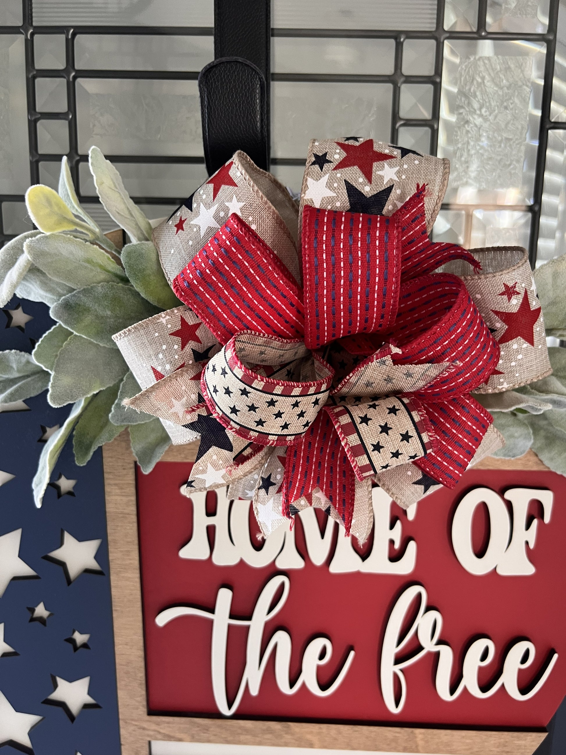 Decorative sign with a red, white, and blue bow and 'Home of the Free' text.