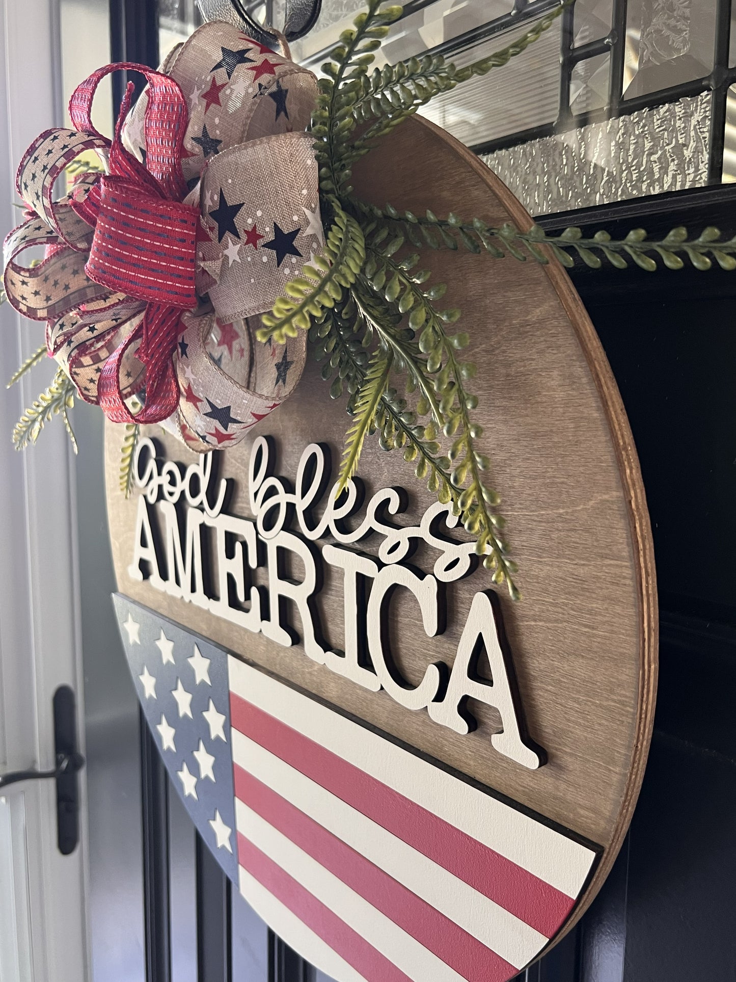 Decorative sign with 'God bless America' text and American flag design on a birchwood sign. 