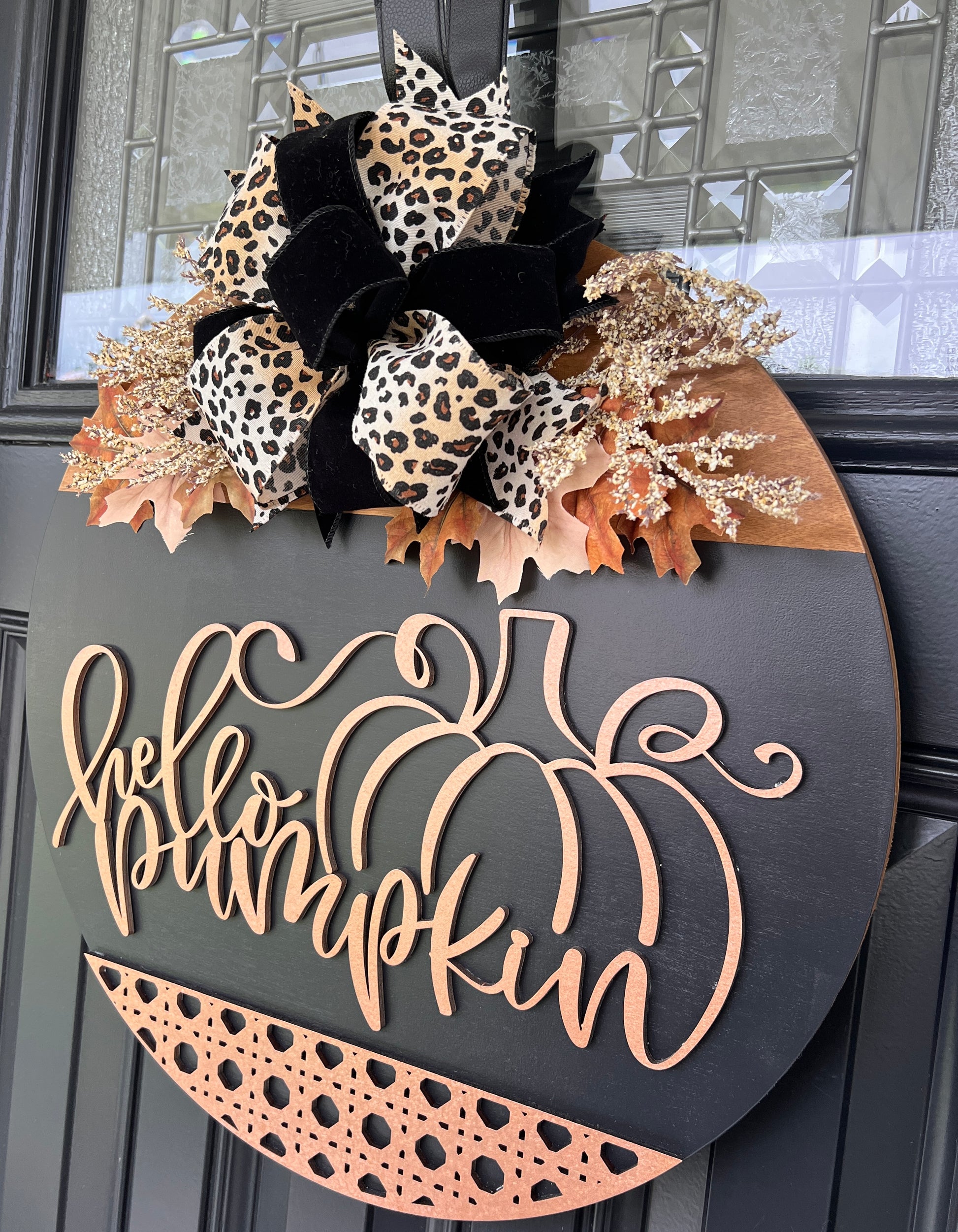 Hello Pumpkin black door hanger close up showing natural wood laser cut pumpkin and script lettering