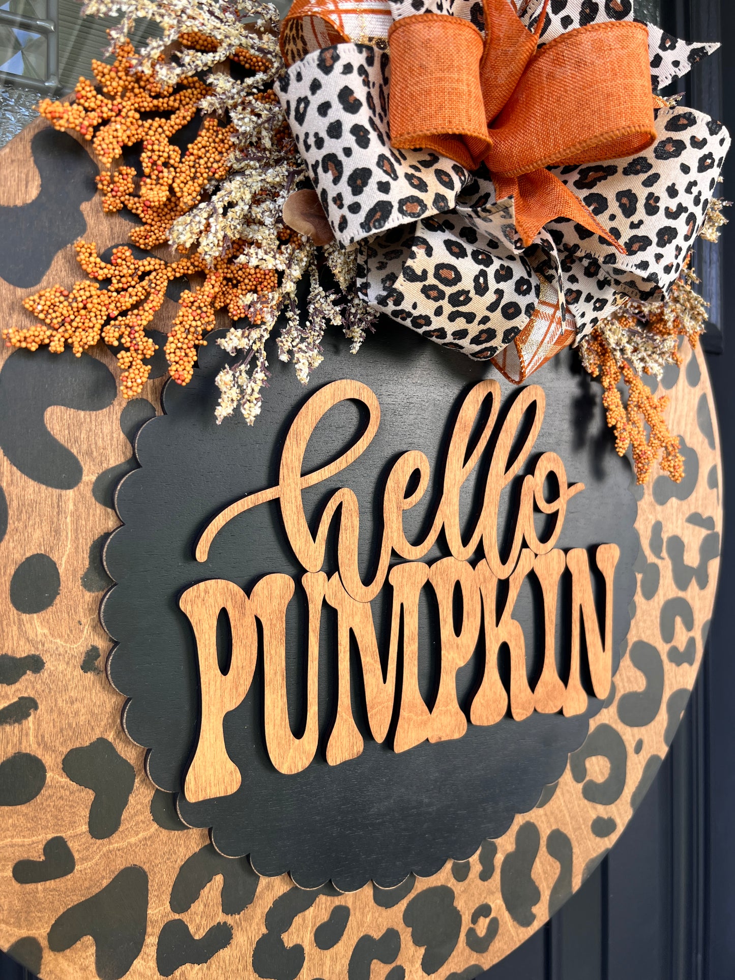 Hello Pumpkin leopard print door hanger close up showing natural wood laser cut lettering on black scalloped overlay with leopard print bow