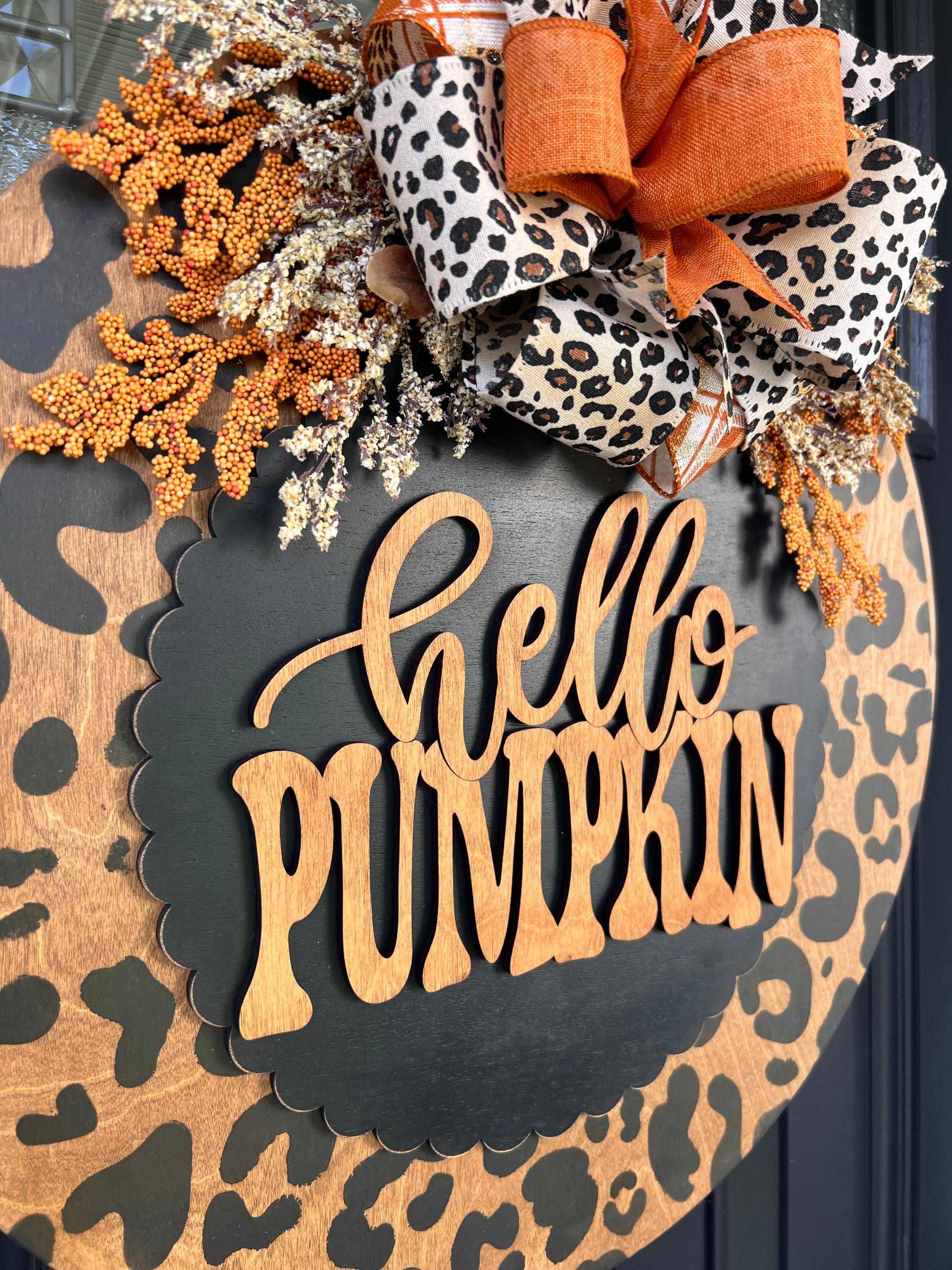 Hello Pumpkin leopard print door hanger close up showing natural wood laser cut lettering on black scalloped overlay with leopard print bow
