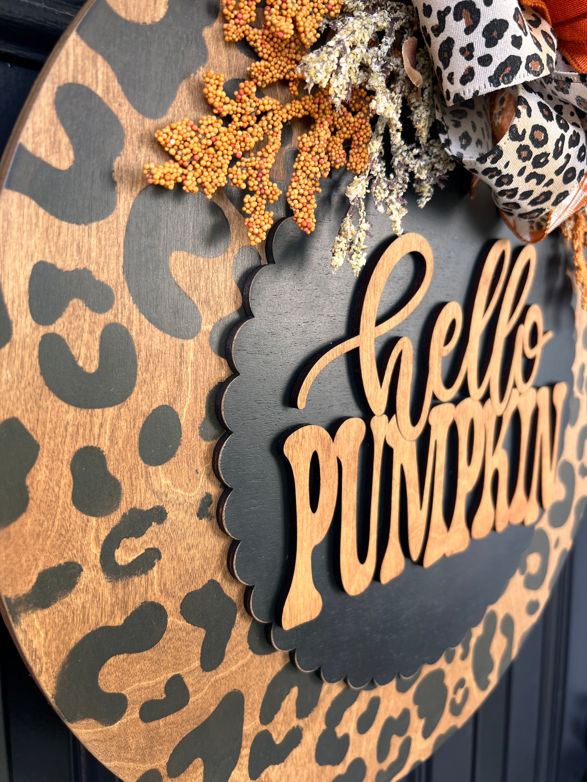 Hello Pumpkin leopard print door hanger angled close up showing hello script and PUMPKIN block lettering on black scalloped oval
