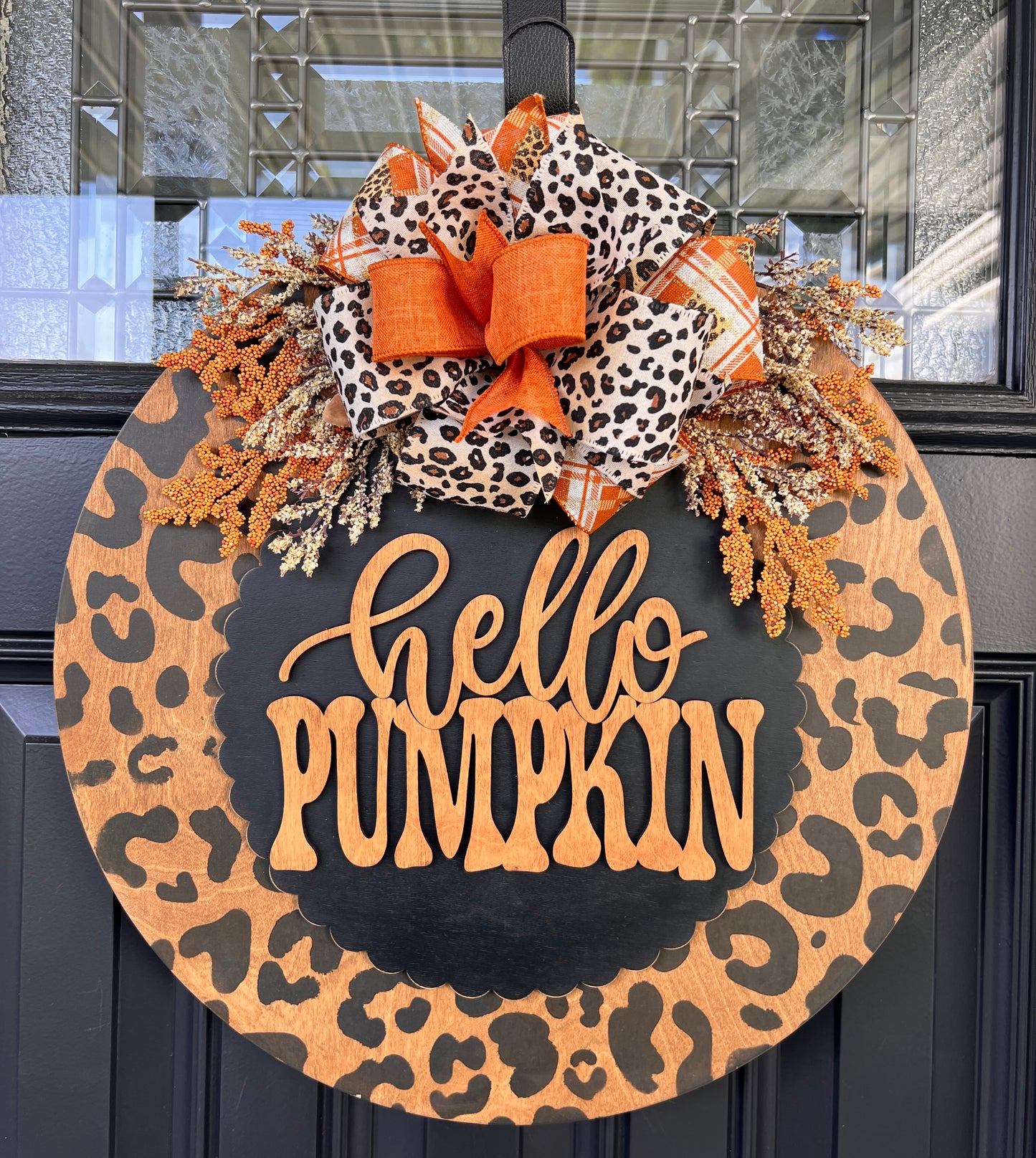 Hello Pumpkin leopard print door hanger full view on black door showing dried berry and floral spray detail with bow