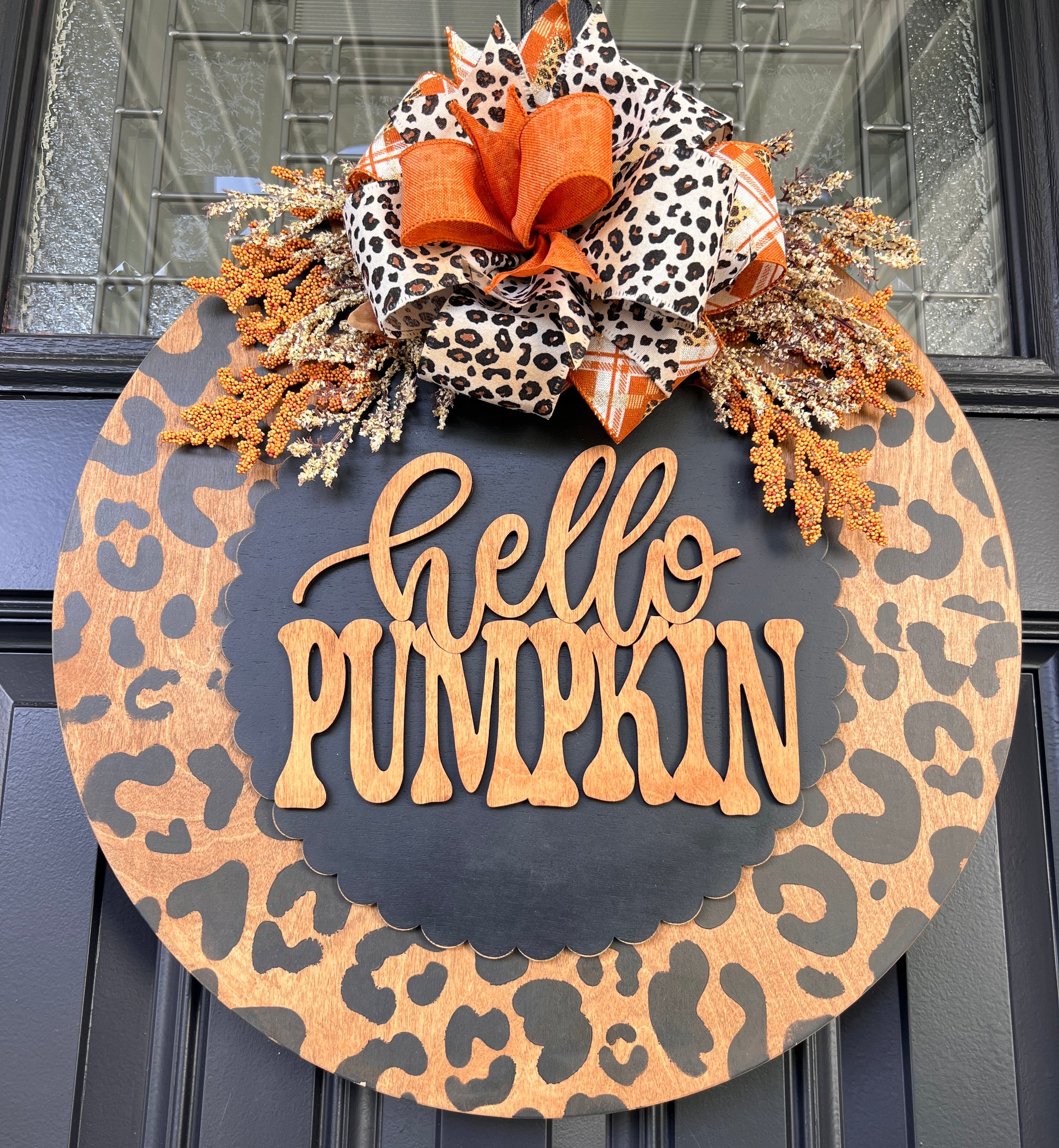 Hello Pumpkin leopard print door hanger full view on black door showing complete design with warm amber and cream dried floral sprays
