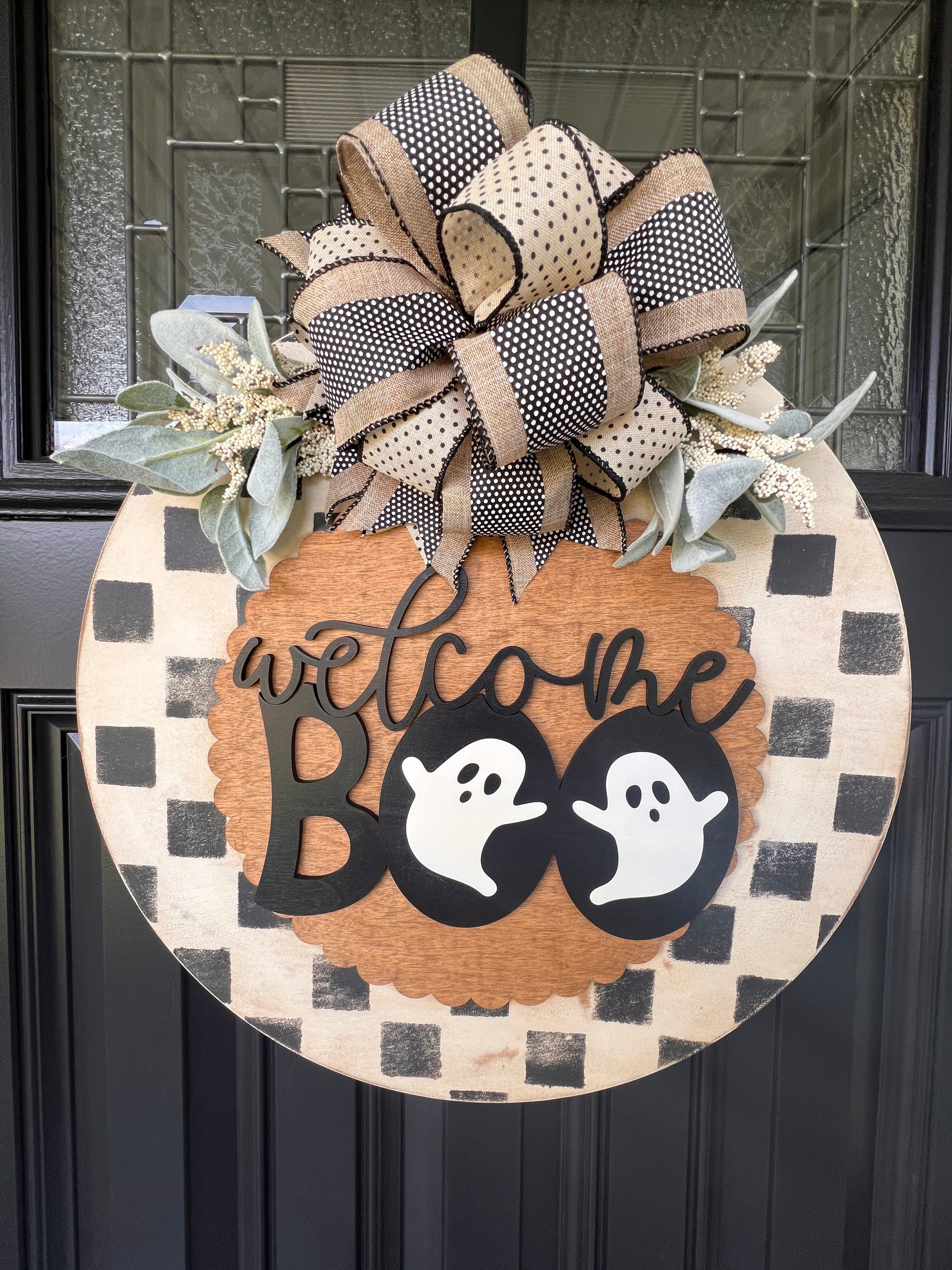 Handmade Welcome Boo Halloween door hanger with ghost accents, black and cream checkered background, layered wood lettering, designer bow, and fall front porch décor.