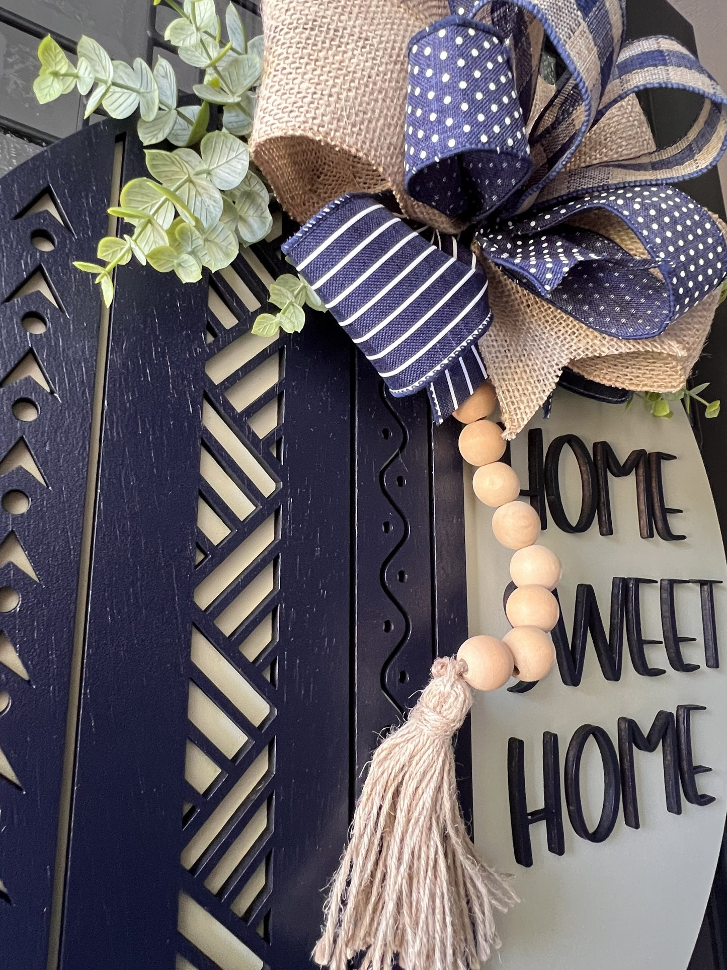Dark Blue and Neutral Door hanger wreath with a bow, tassel, and 'Home Sweet Home' sign on a door.