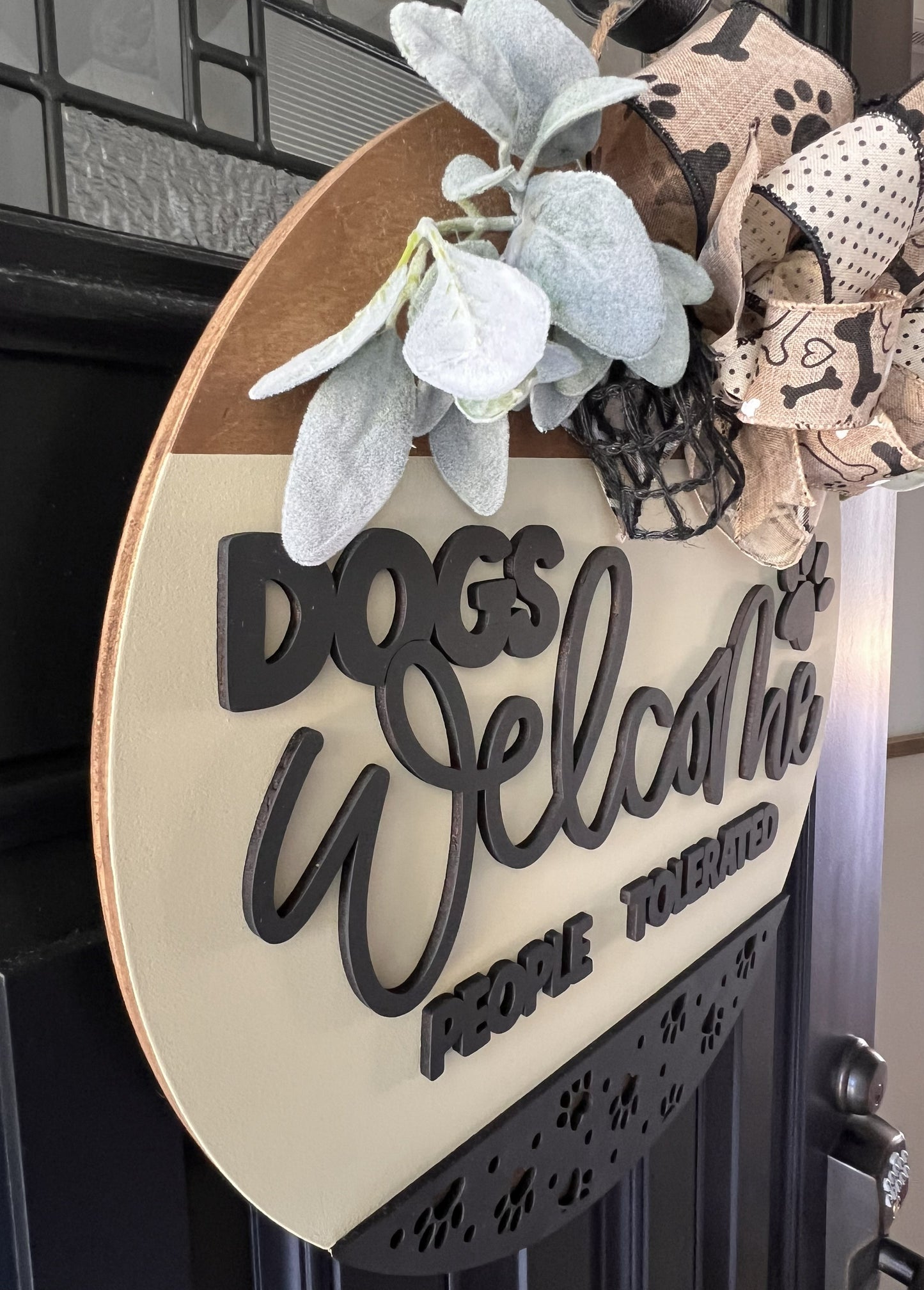 Decorative sign with 'Dogs Welcome' text on a birchwood door hanger with bow and floral accents. 