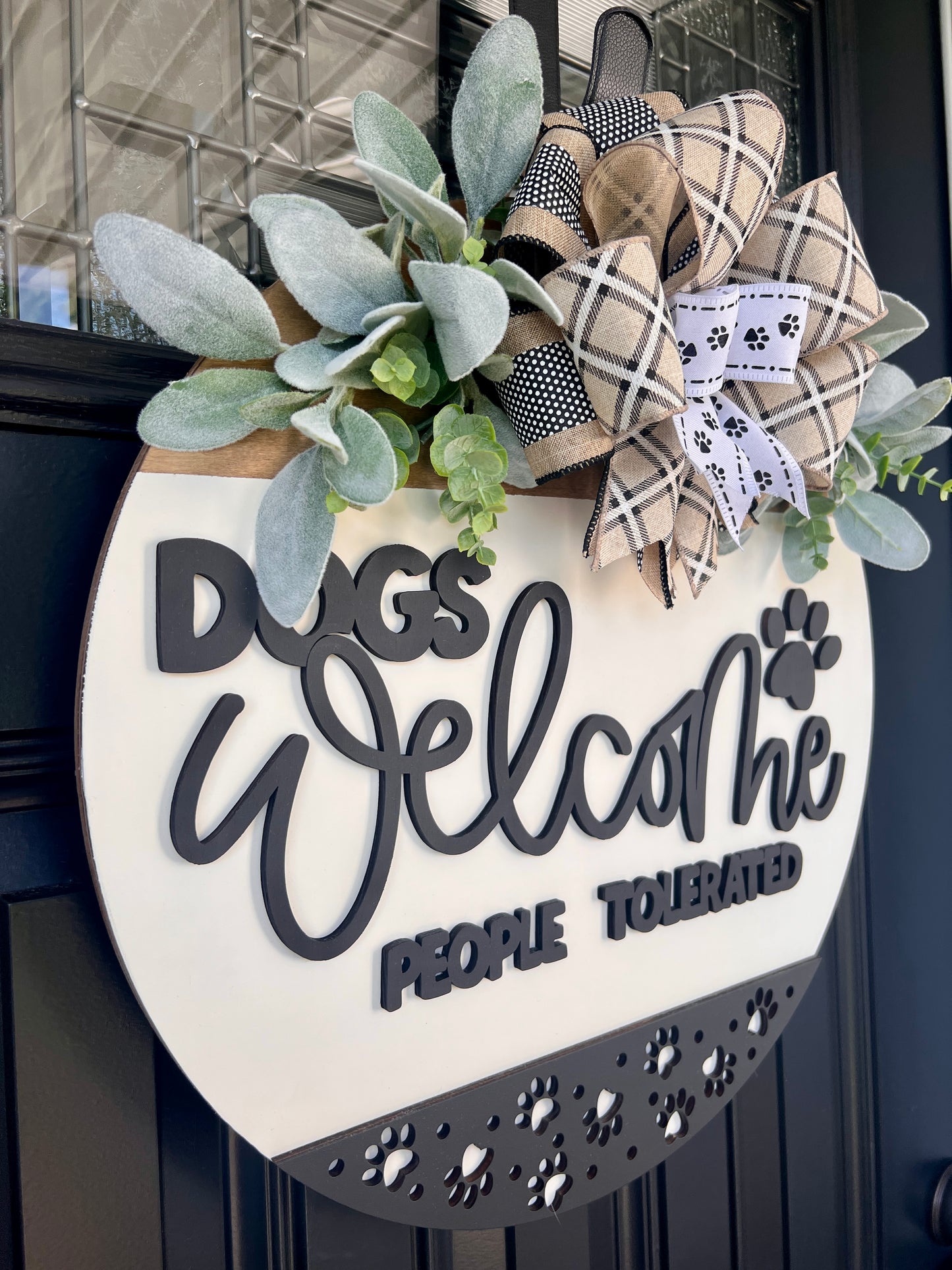 Dogs Welcome People Tolerated door hanger close up showing 3D lettering and paw print border with plaid and paw print bow and lambs ear greenery