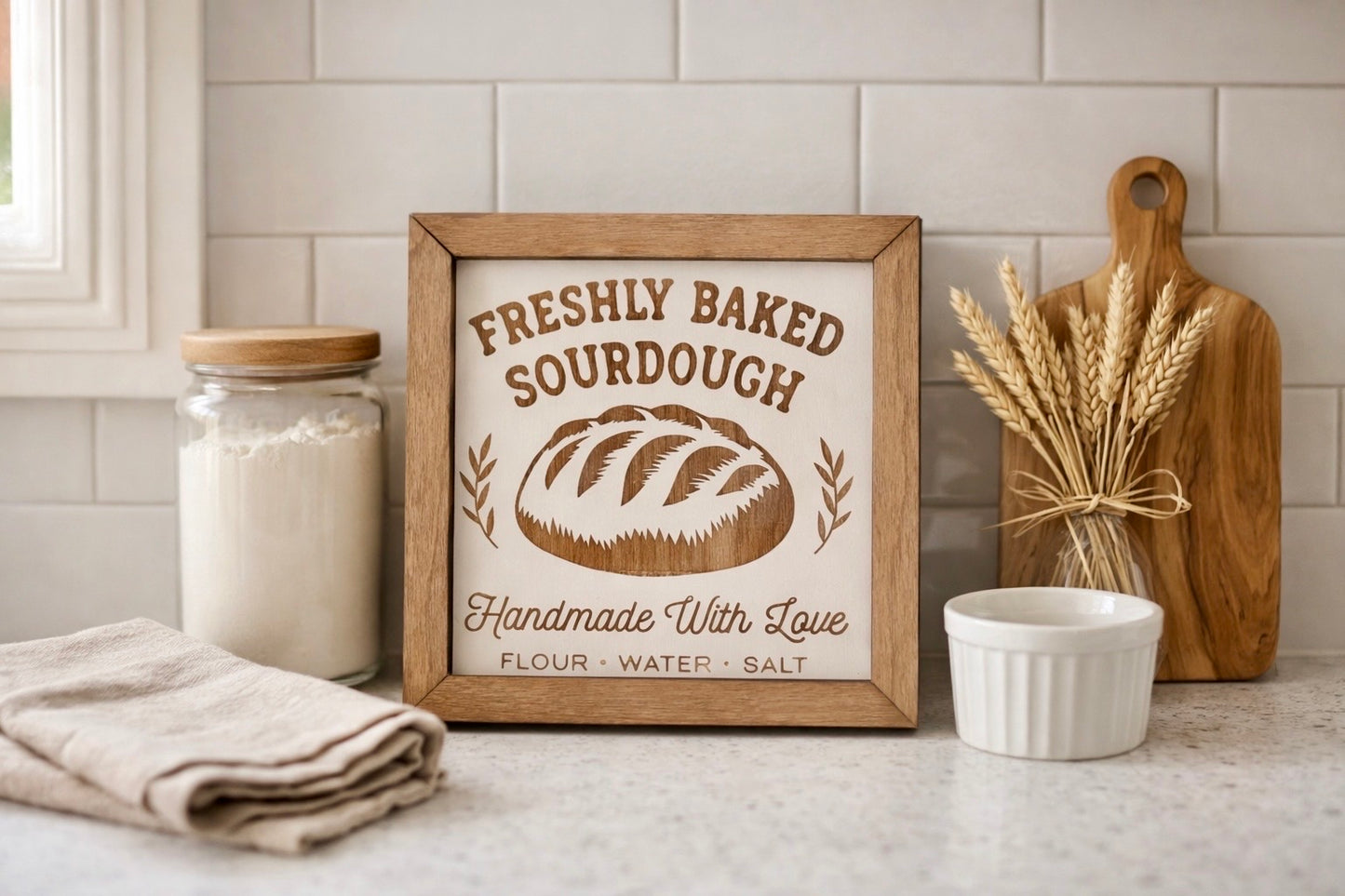 Freshly Baked Sourdough engraved birch wood sign styled on a kitchen counter with flour jar, linen towel, and wheat stems