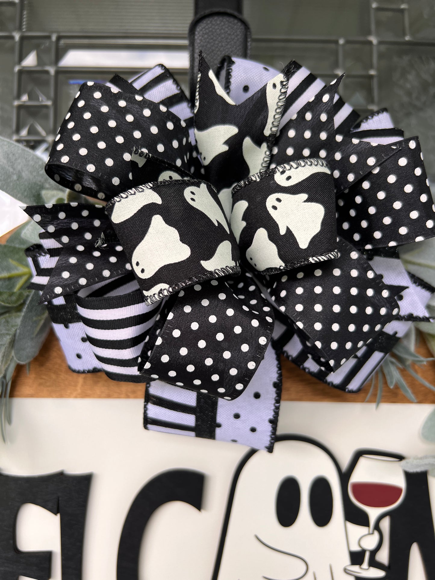 Close up of layered Halloween bow with ghost print polka dot and black white stripe ribbons
