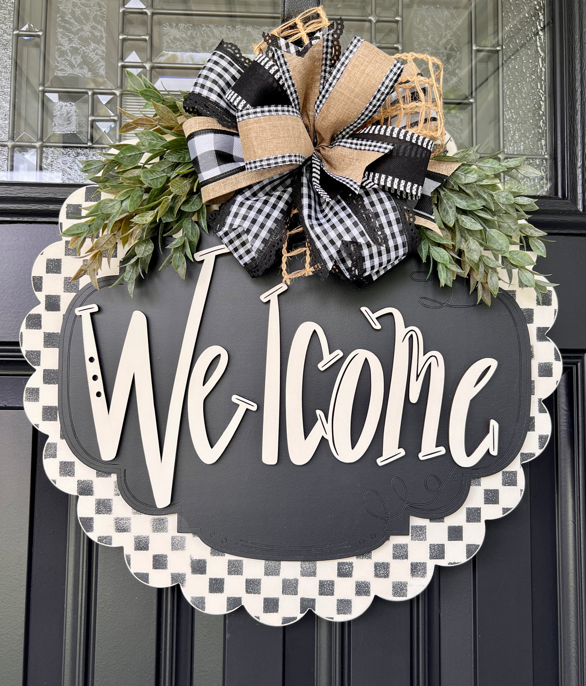 Side angle of 3D layered wood Welcome lettering on black and white checkered scalloped door hanger