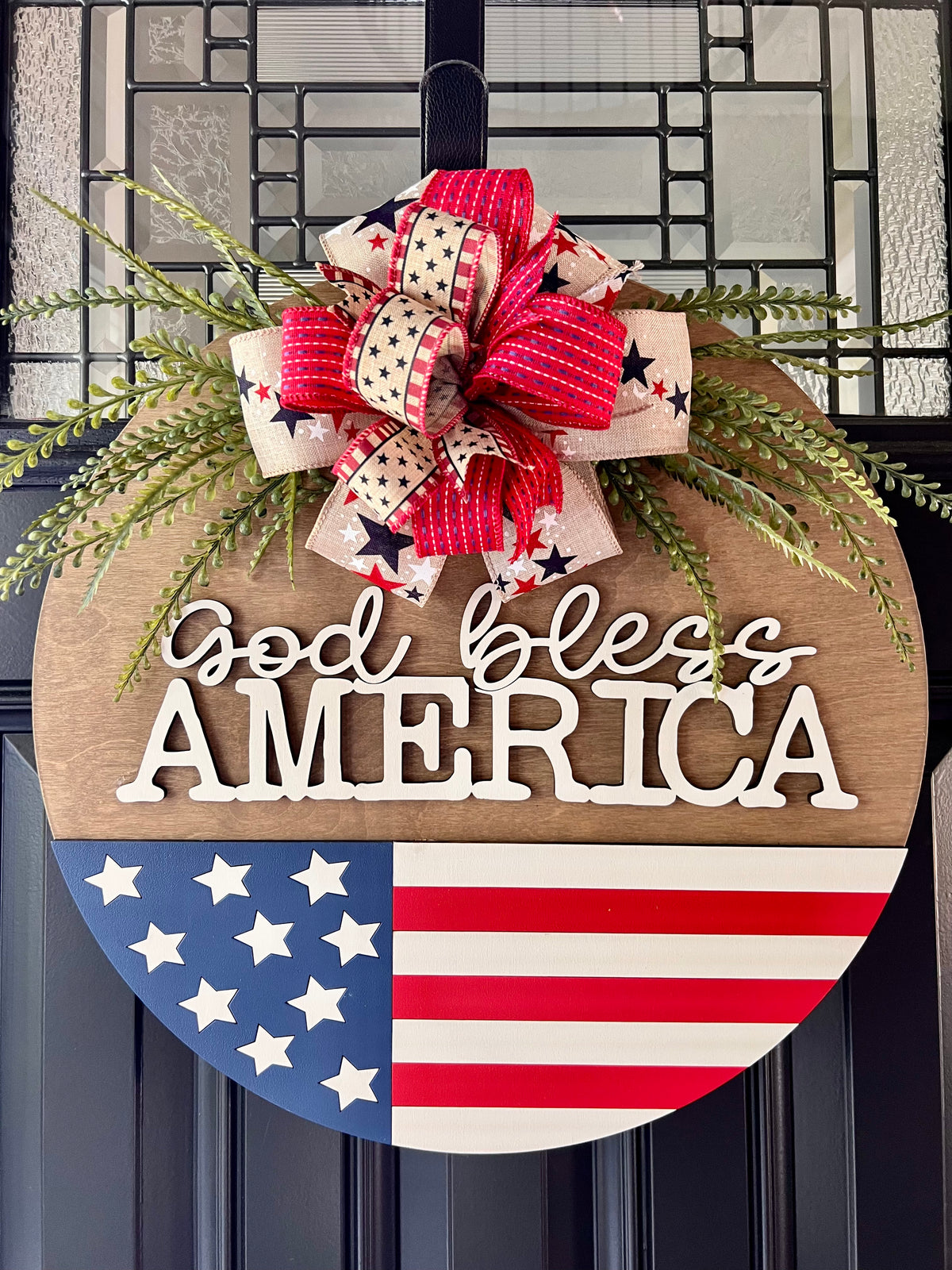 Decorative door hanger with 'God bless America' text and American flag design.