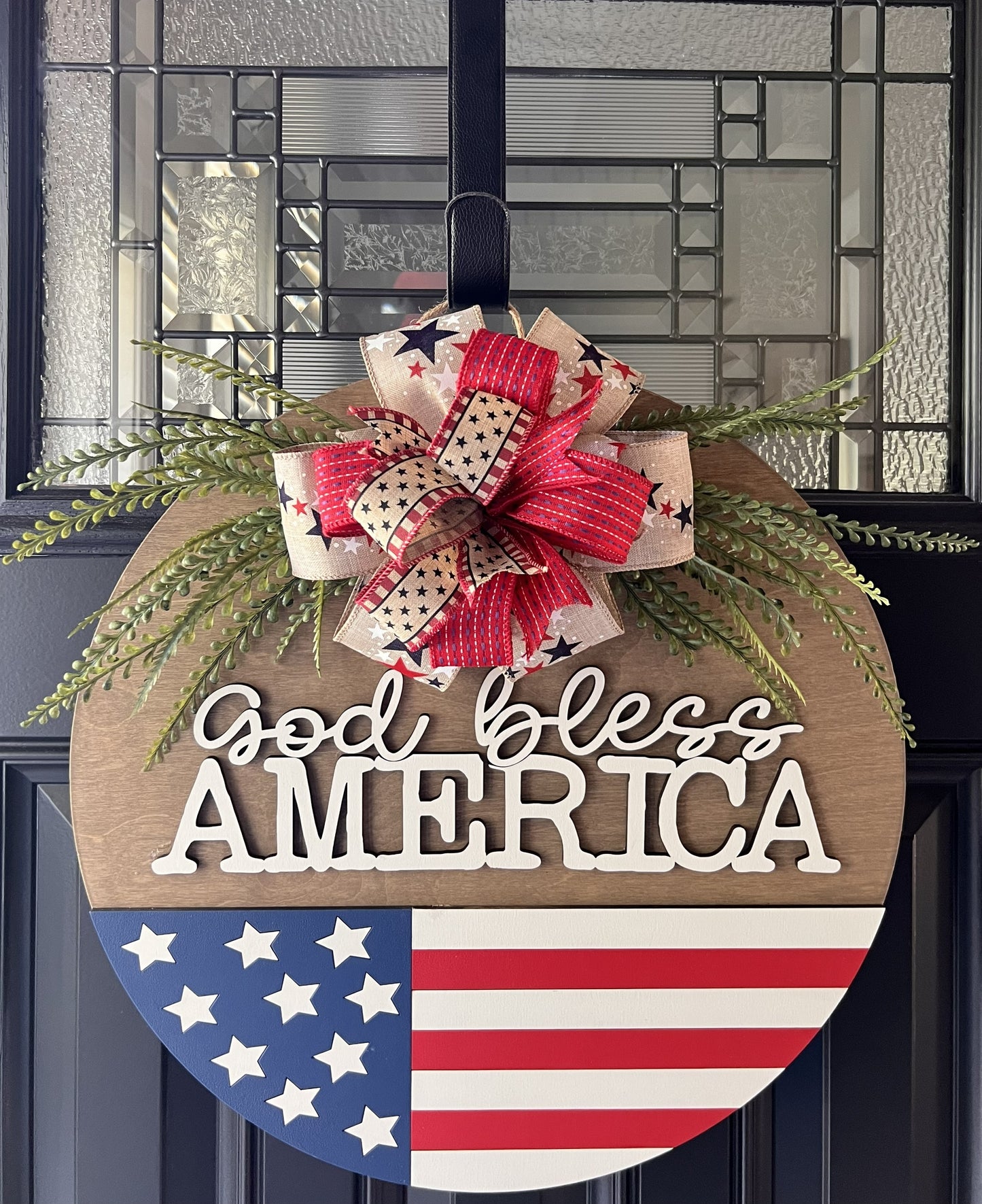 Decorative door hanger with 'God bless America' text and American flag design.