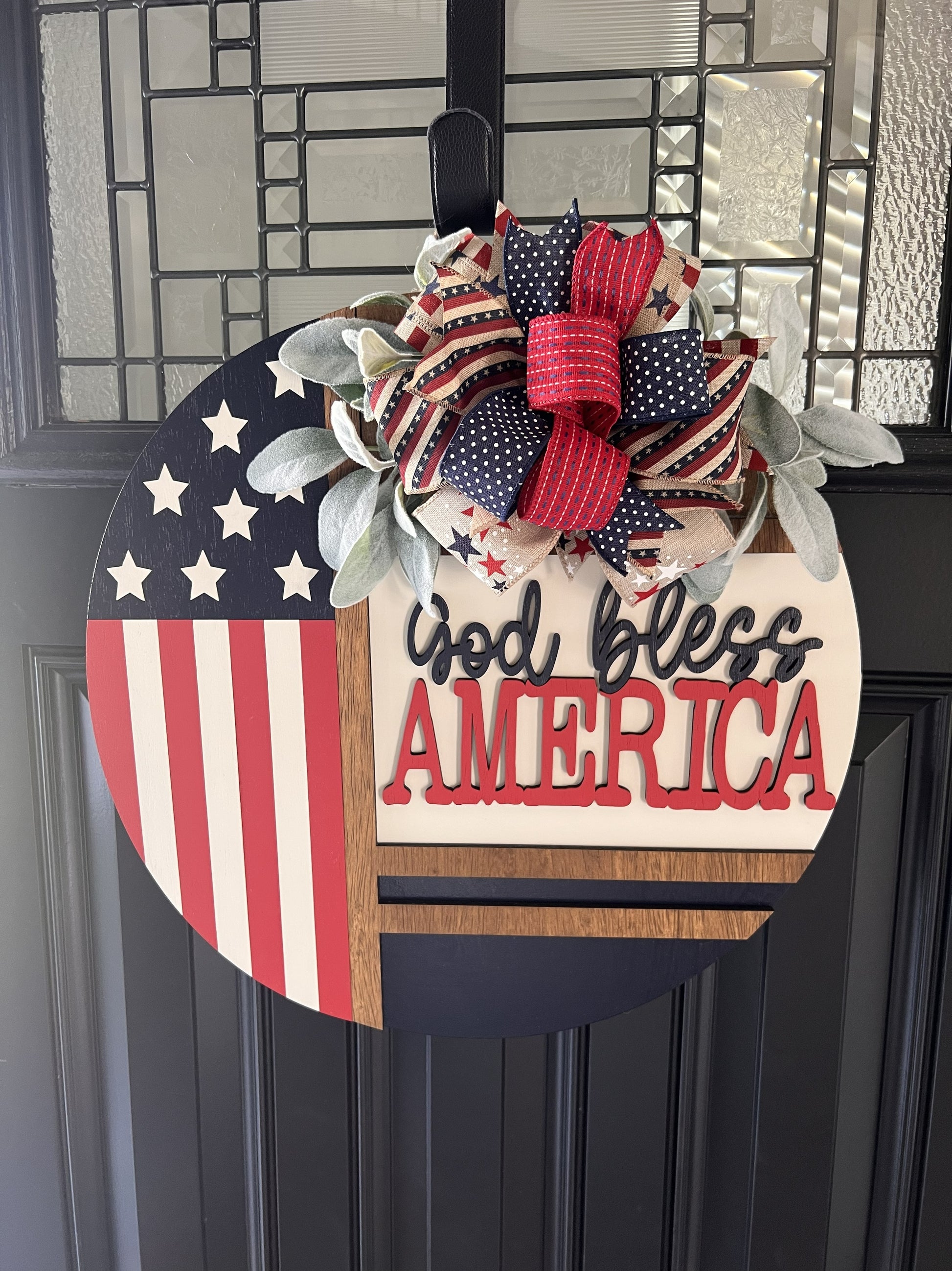 Americana door hanger with American flag design and 'God bless America' text on a black door.