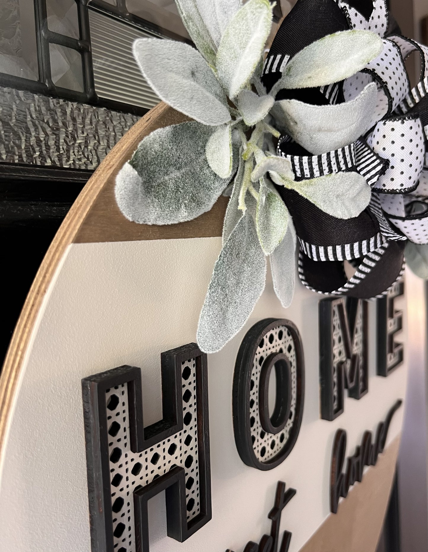 “Home Sweet Home black and white wooden door hanger with layered lettering, decorative bow and greenery on front door”