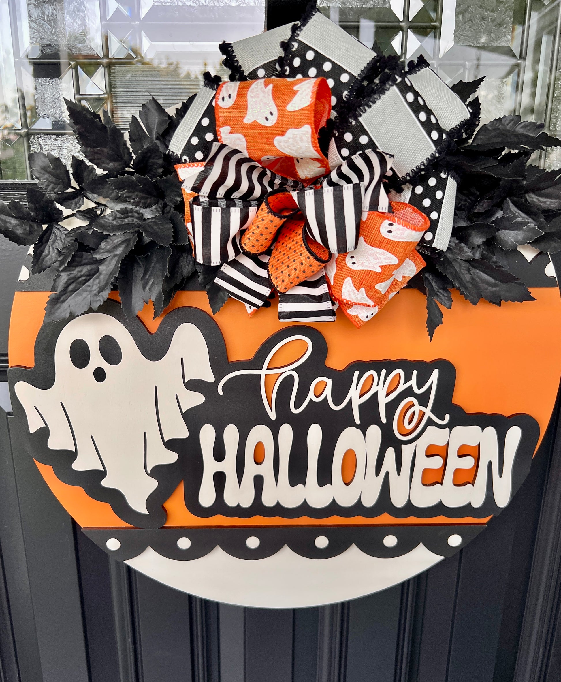 Happy Halloween ghost door hanger full front view on black door showing complete 18 inch orange round design