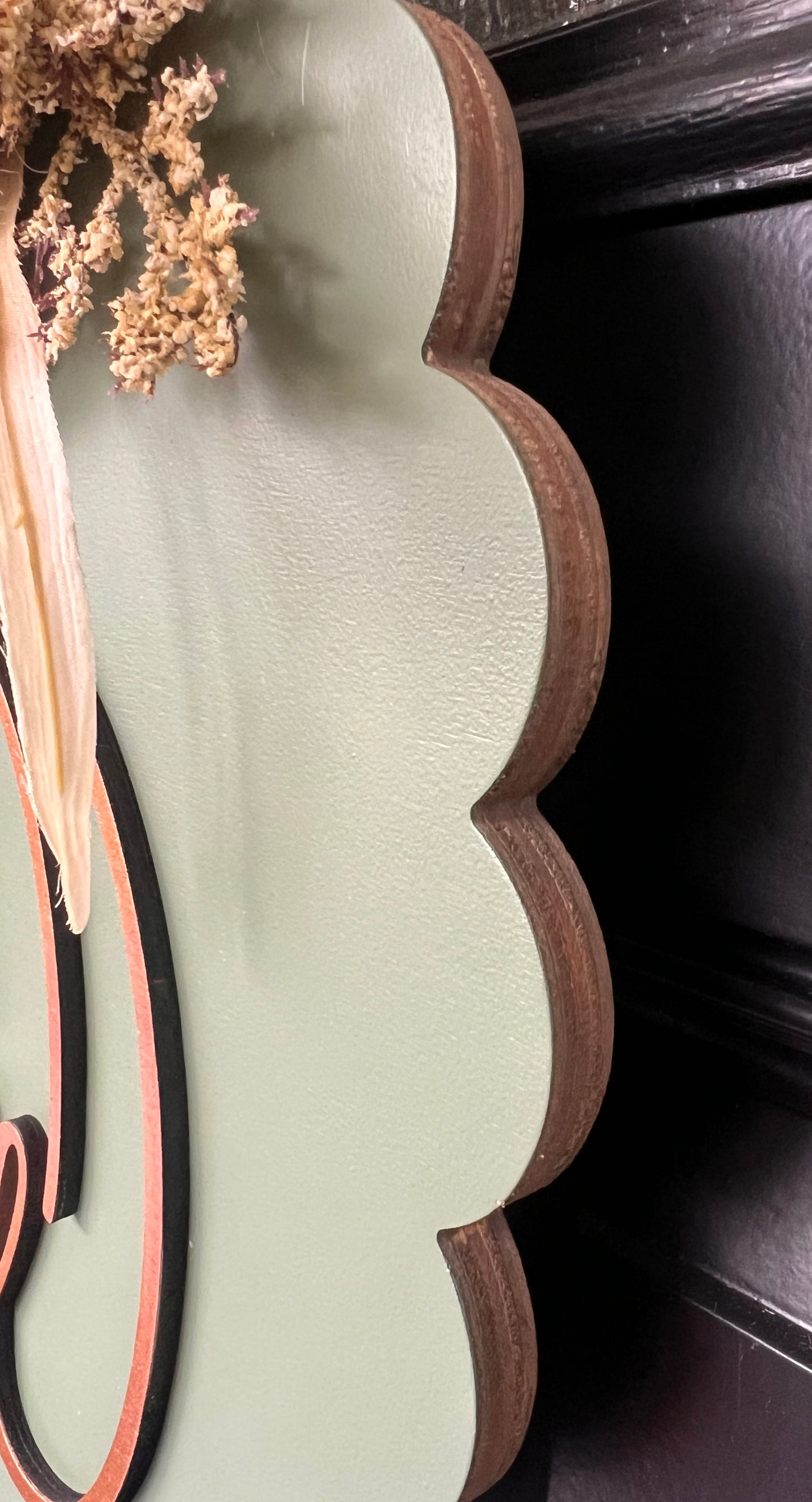 Close up side view of scalloped edge and wood grain detail on sage hello fall door hanger