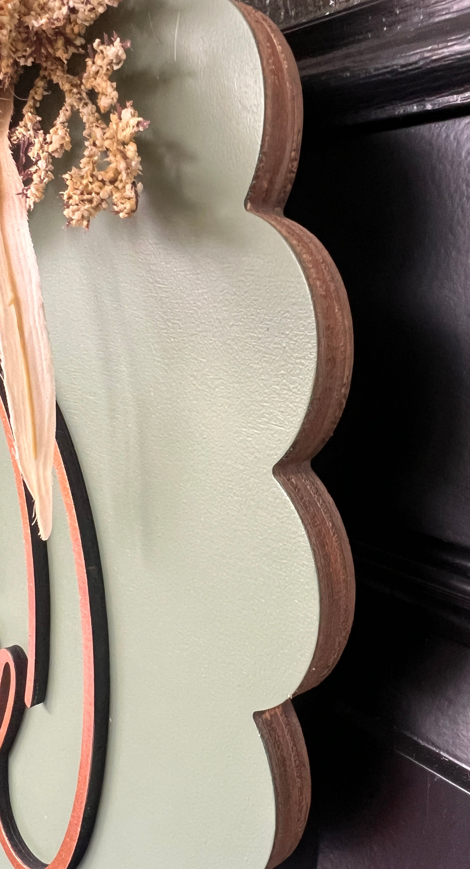 Close up side view of scalloped edge and wood grain detail on sage hello fall door hanger