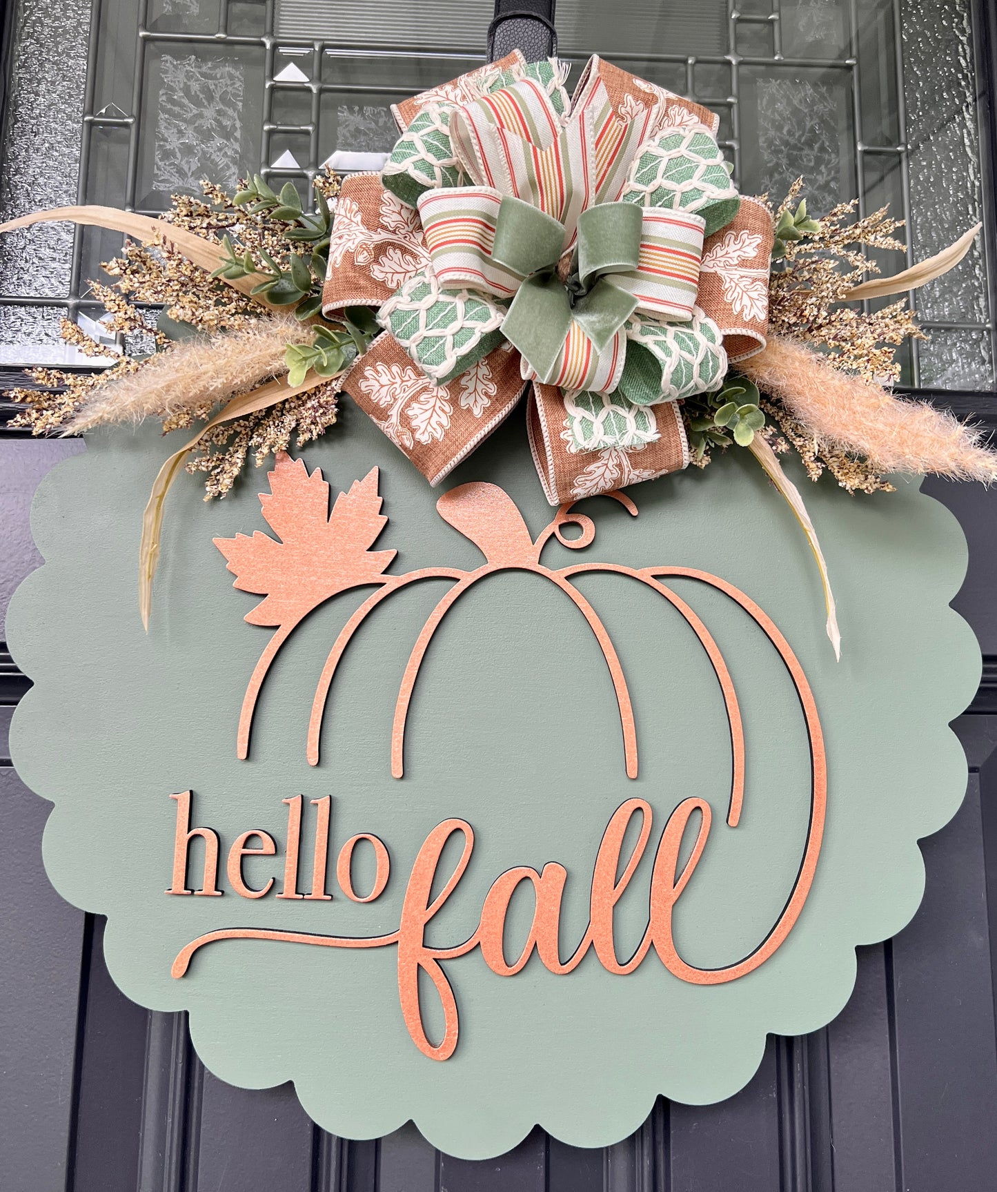18 inch sage and copper hello fall scalloped door hanger with pumpkin design and layered bow arrangement with pampas grass on black front door
