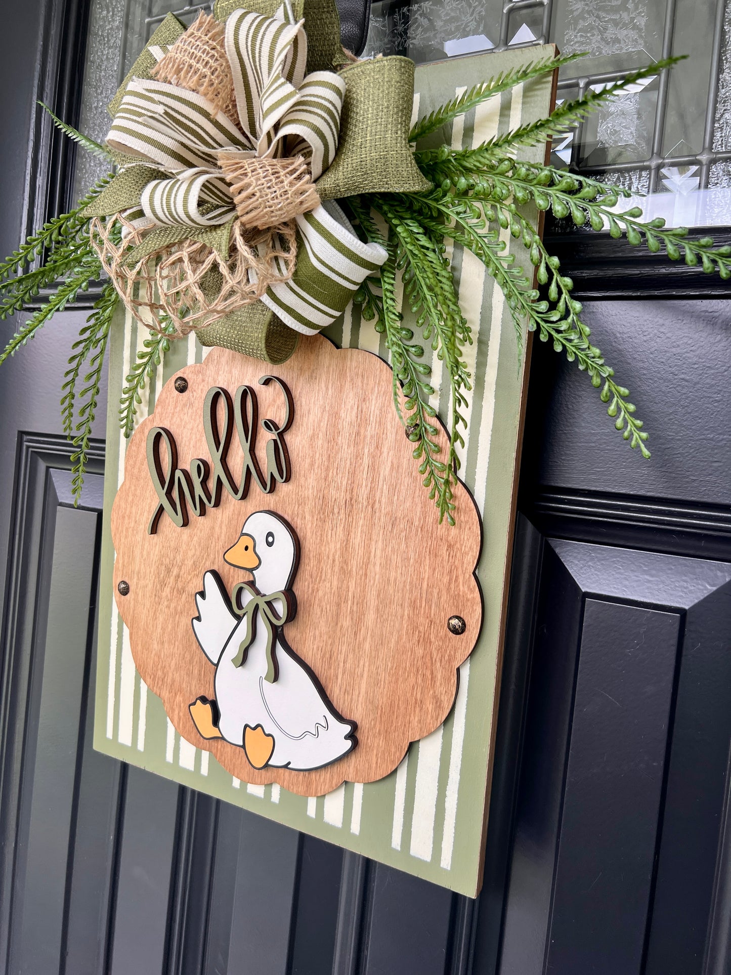 Hello Goose door sign close up of white goose with sage bow tie on warm natural birchwood