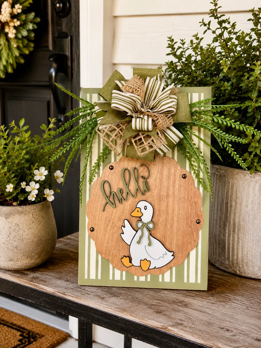 Hello Goose olive green pinstripe door sign styled on porch with greenery and white flowering plants