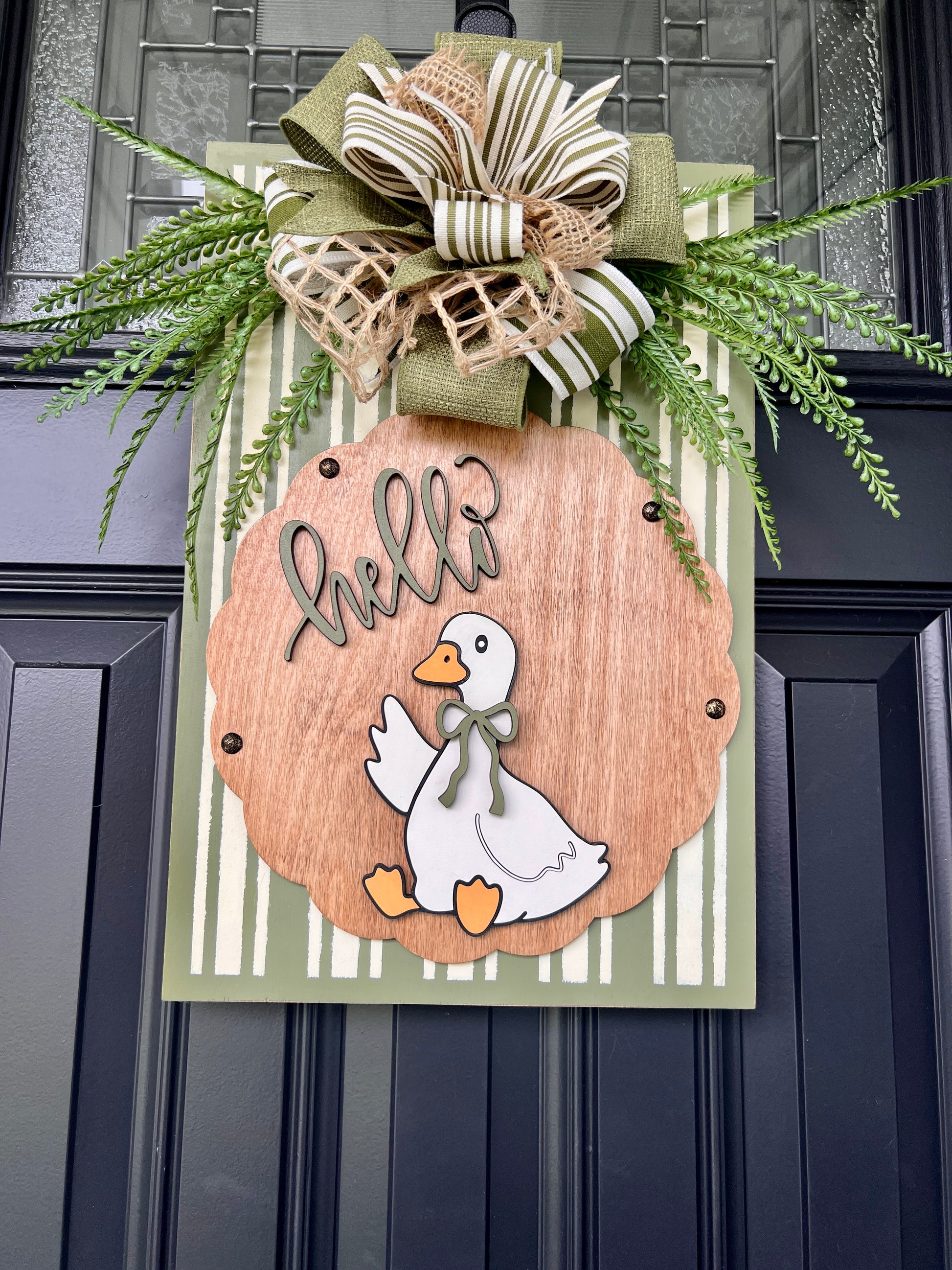 Hello Goose door sign close up showing 3D sage hello script and white goose with sage bow tie on birchwood round