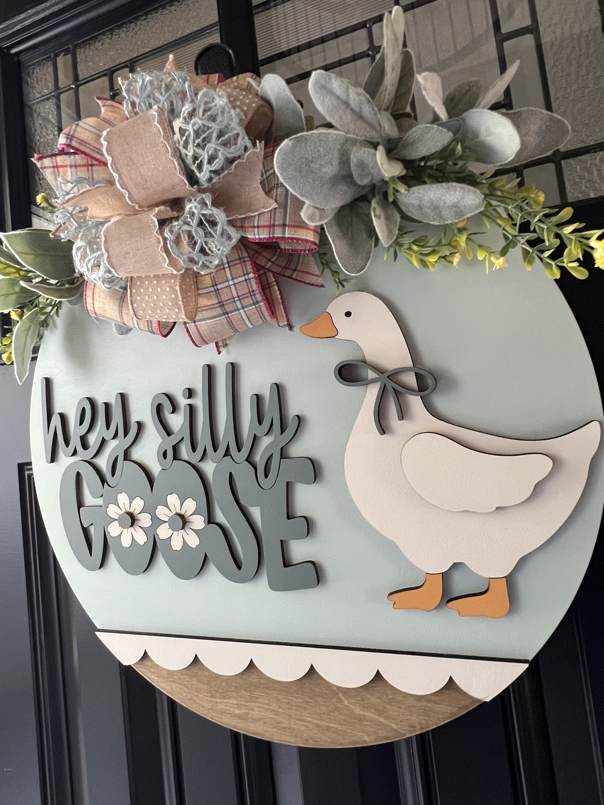 Decorative sign with a goose and floral elements on a neutral background