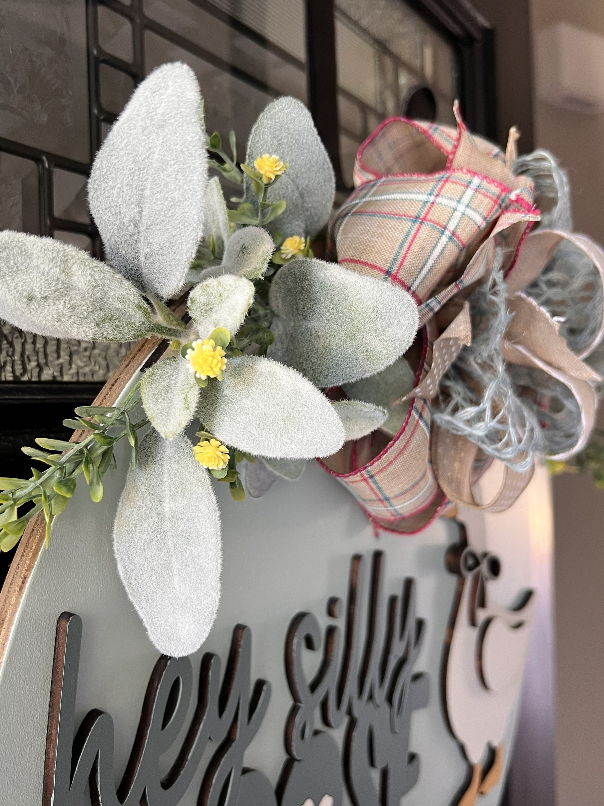 Decorative wreath with plaid ribbon and floral elements on a birchwood door hanger 