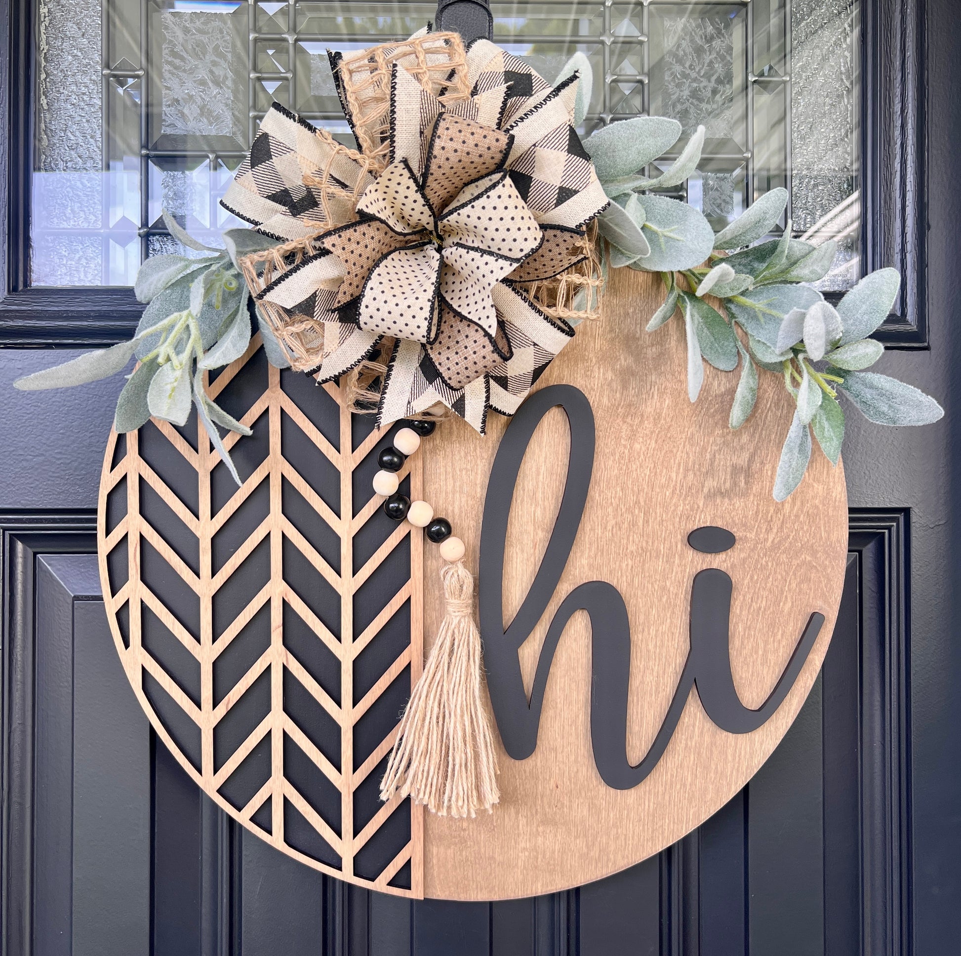 Decorative door hanger with floral elements and 'hi' text on a dark door.