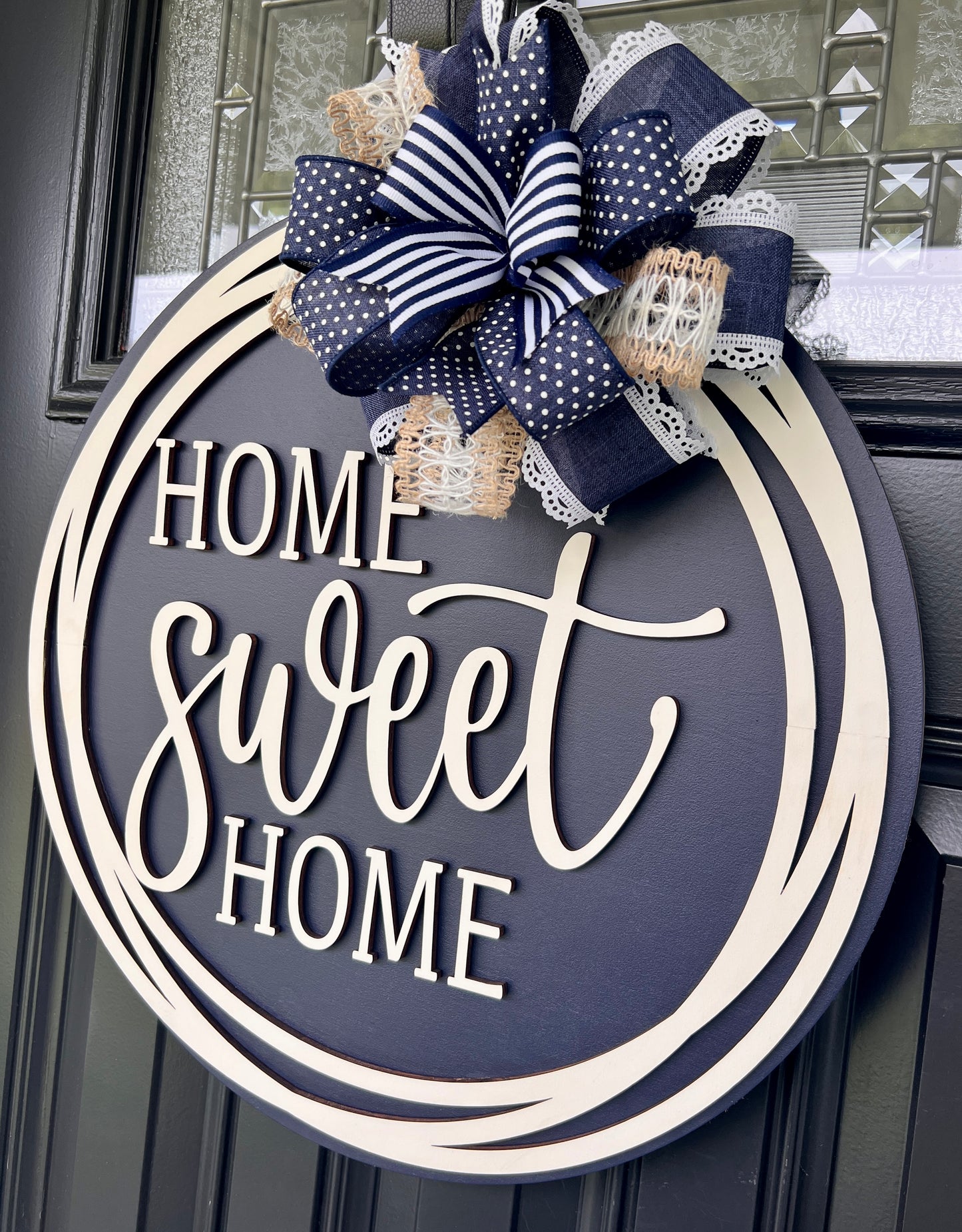 Home Sweet Home navy blue circle framed door hanger on black front door with layered navy polka dot grid and jute burlap bow
