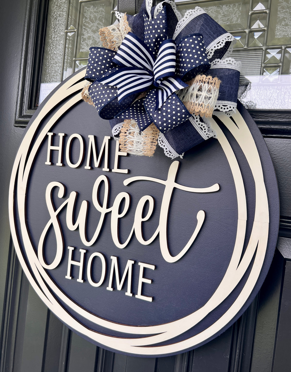 Home Sweet Home navy blue circle framed door hanger on black front door with layered navy polka dot grid and jute burlap bow