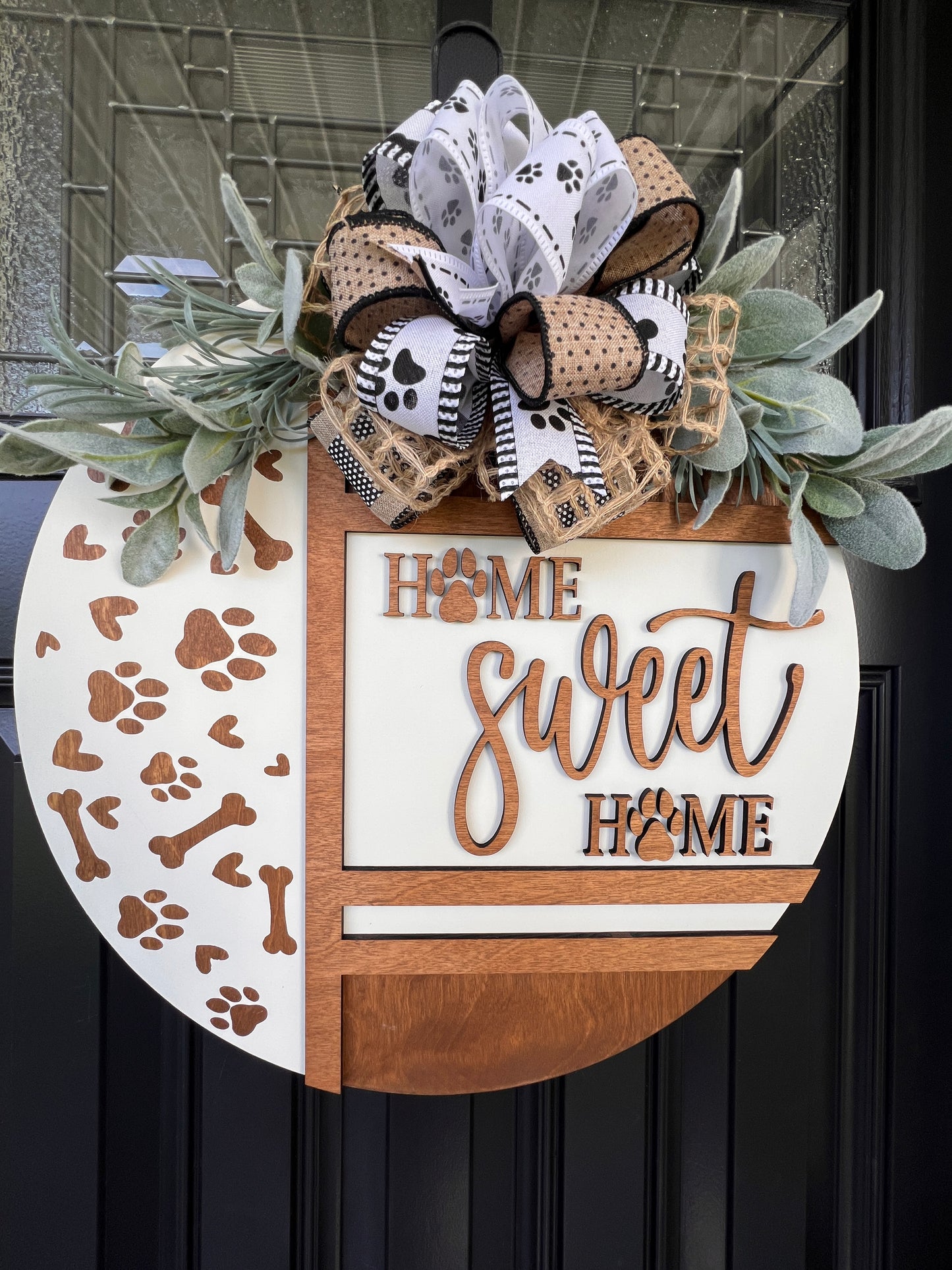 Handmade Home Sweet Home dog lover door hanger featuring laser-cut paw prints, dog bone accents, stained birchwood details, greenery, and a coordinating designer bow.