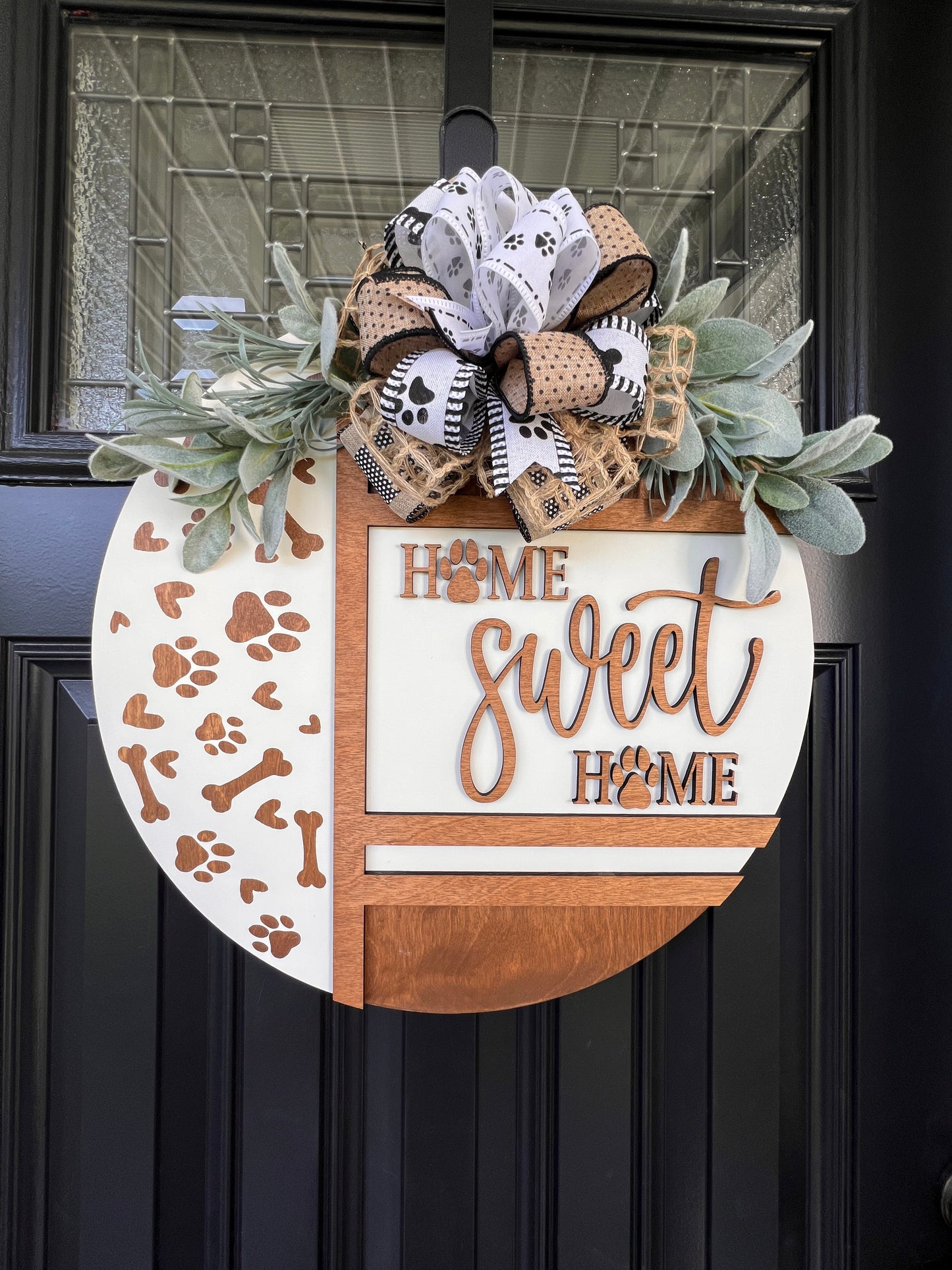 Handmade Home Sweet Home dog lover door hanger featuring laser-cut paw prints, dog bone accents, stained birchwood details, greenery, and a coordinating designer bow.