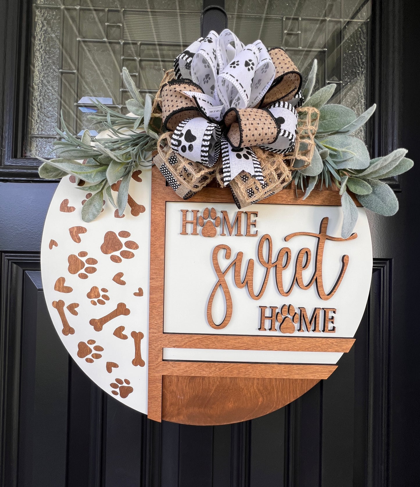 Handmade Home Sweet Home dog lover door hanger featuring laser-cut paw prints, dog bone accents, stained birchwood details, greenery, and a coordinating designer bow.

