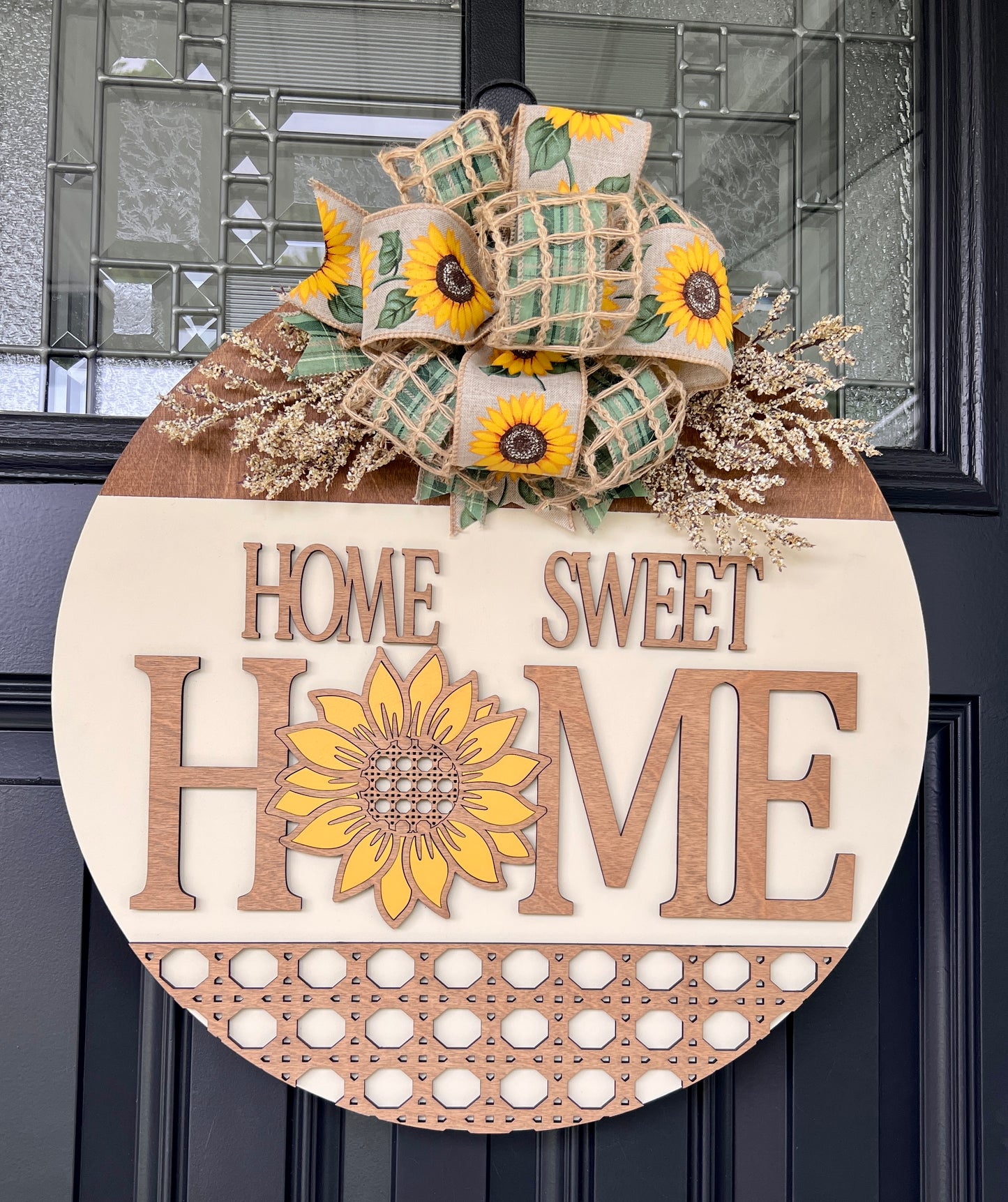 Home Sweet Home sunflower rattan door hanger full view on black front door with layered sunflower bow and dried cream floral sprays