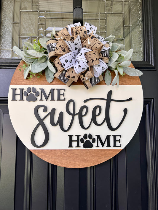 Home Sweet Home paw print door hanger full view on black front door with natural burlap paw print bow and lambs ear greenery
