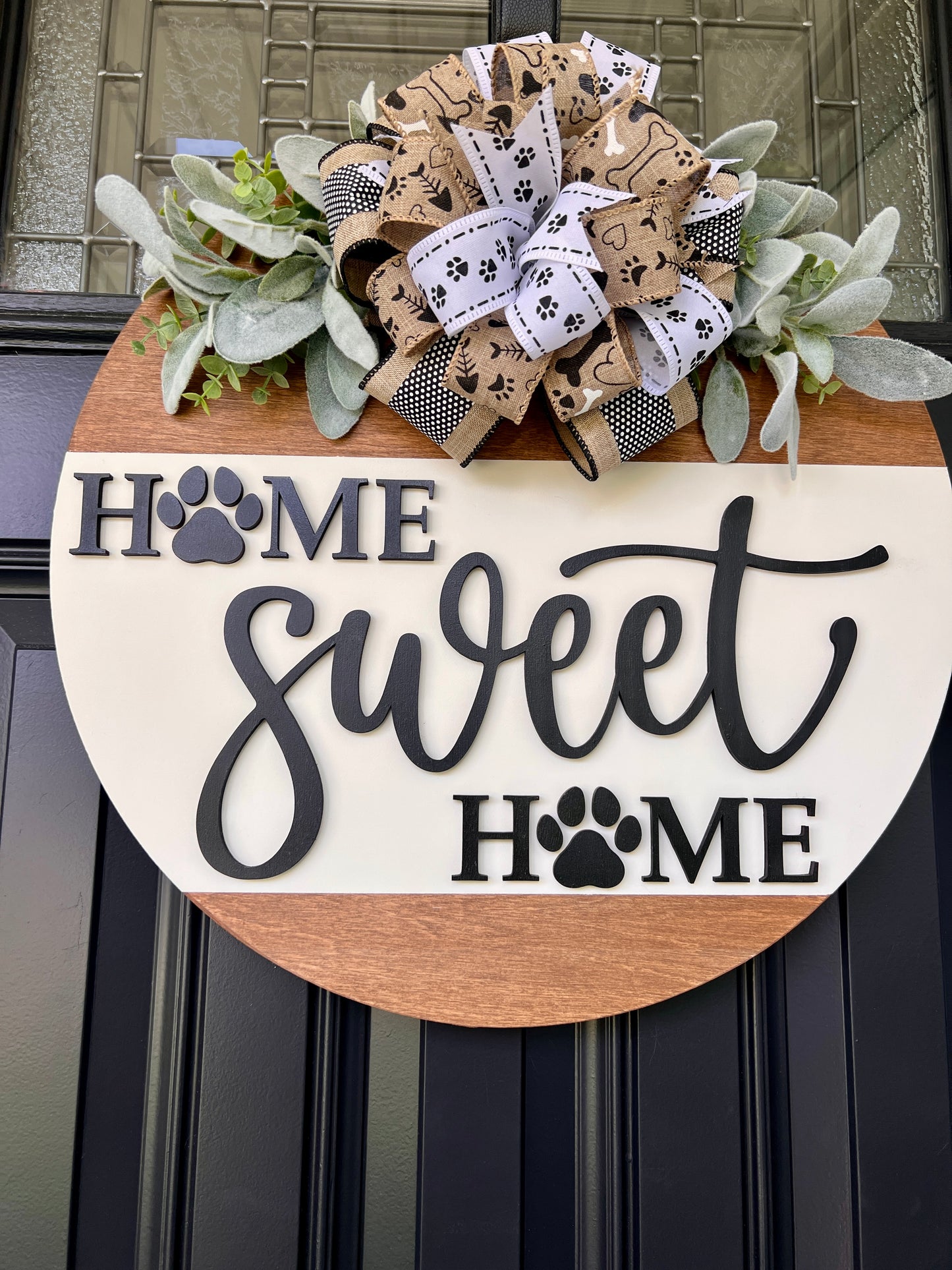 Home Sweet Home paw print door hanger angled view showing depth of 3D charcoal lettering with laser-cut paw print O's on cream panel