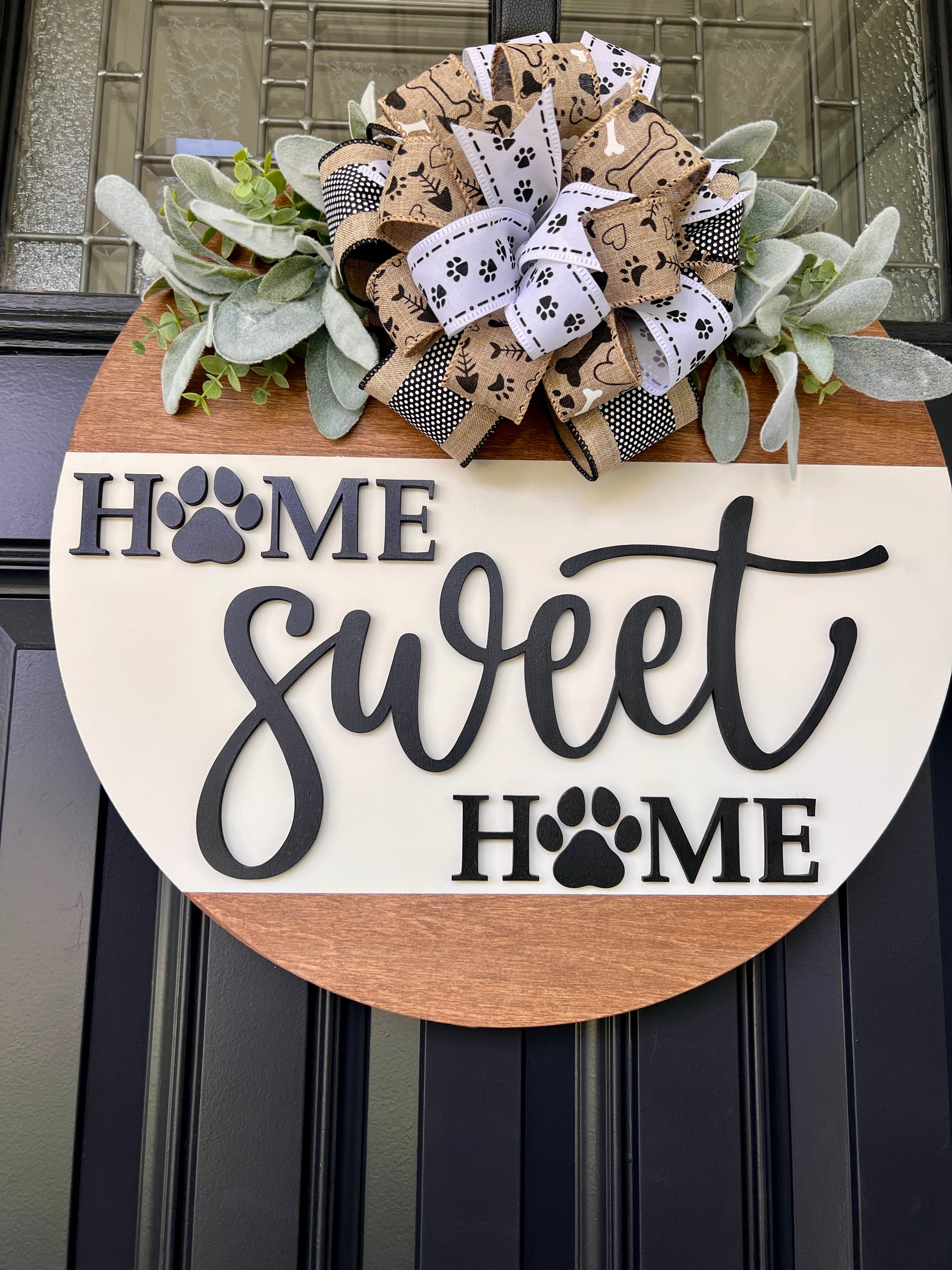 Home Sweet Home paw print door hanger angled view showing depth of 3D charcoal lettering with laser-cut paw print O's on cream panel