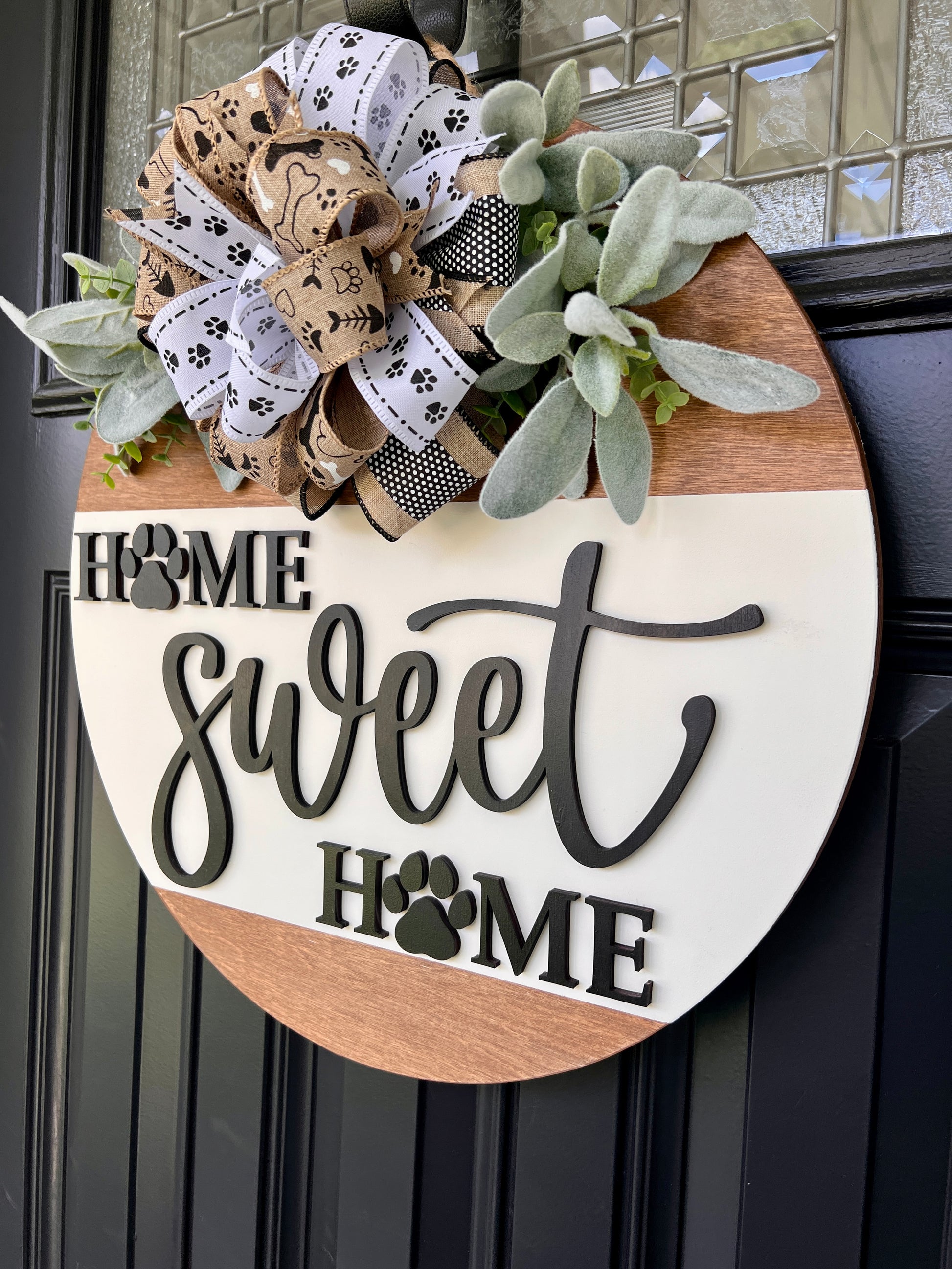 Home Sweet Home paw print door hanger angled close up showing charcoal HOME sweet HOME lettering with paw print cutout detail