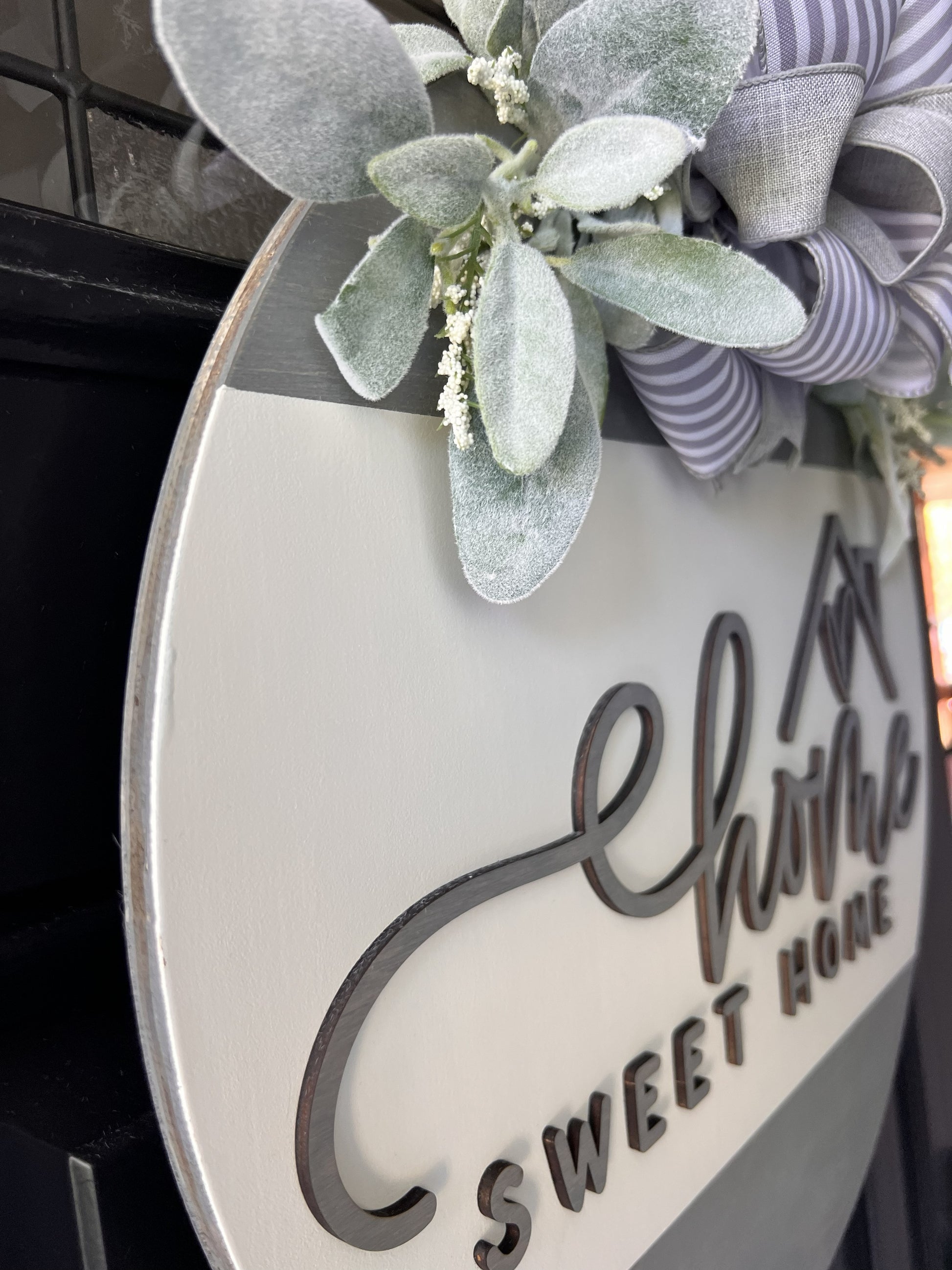 “Home Sweet Home wooden door hanger with neutral tones, layered lettering, bow and greenery on front door
