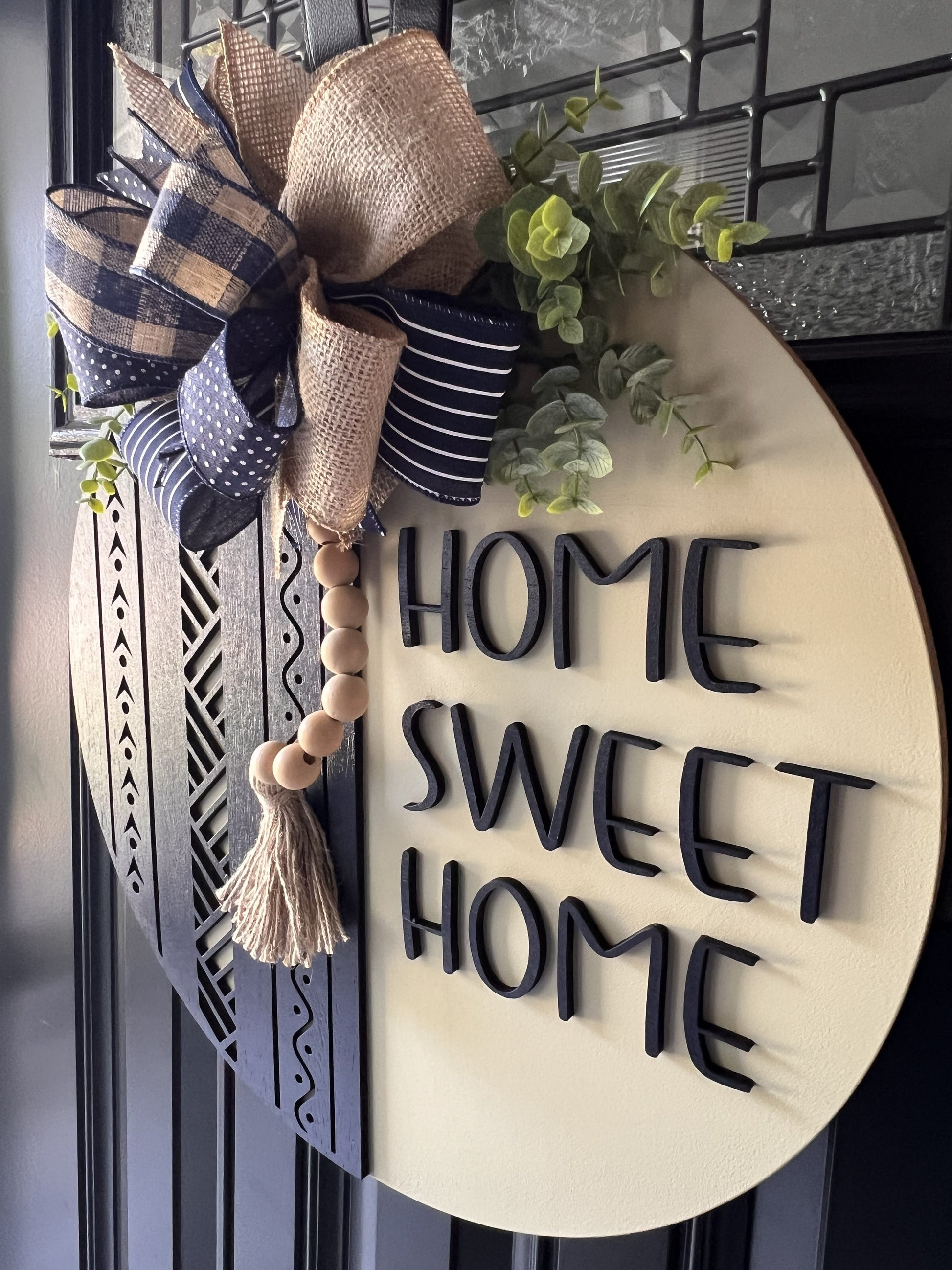 Decorative sign with 'Home Sweet Home' text and a bow on a door.