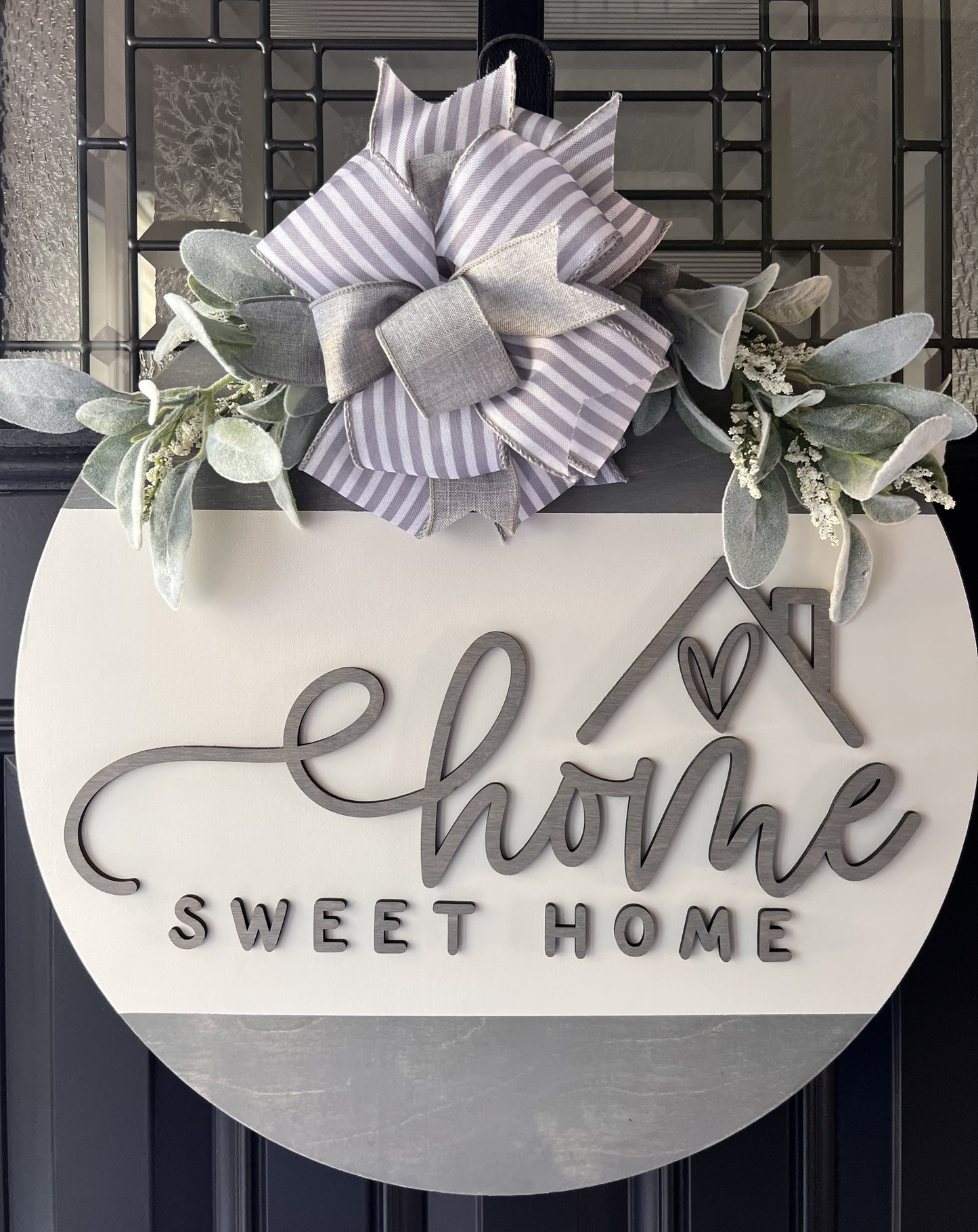 “Home Sweet Home wooden door hanger with neutral tones, layered lettering, bow and greenery on front door