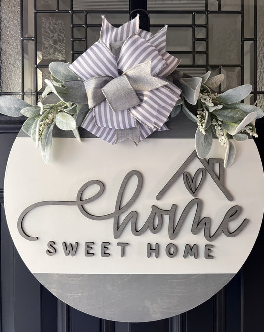 “Home Sweet Home wooden door hanger with neutral tones, layered lettering, bow and greenery on front door