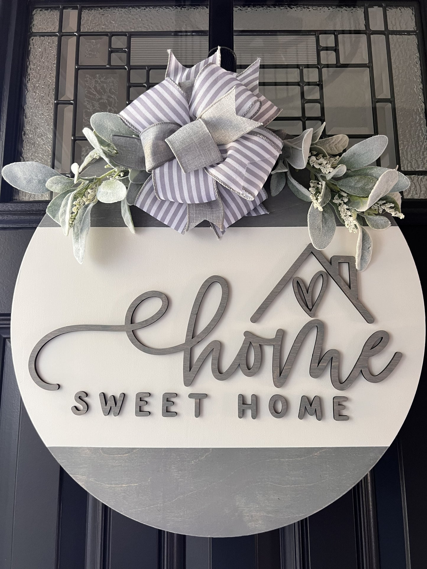 “Home Sweet Home wooden door hanger with neutral tones, layered lettering, bow and greenery on front door
