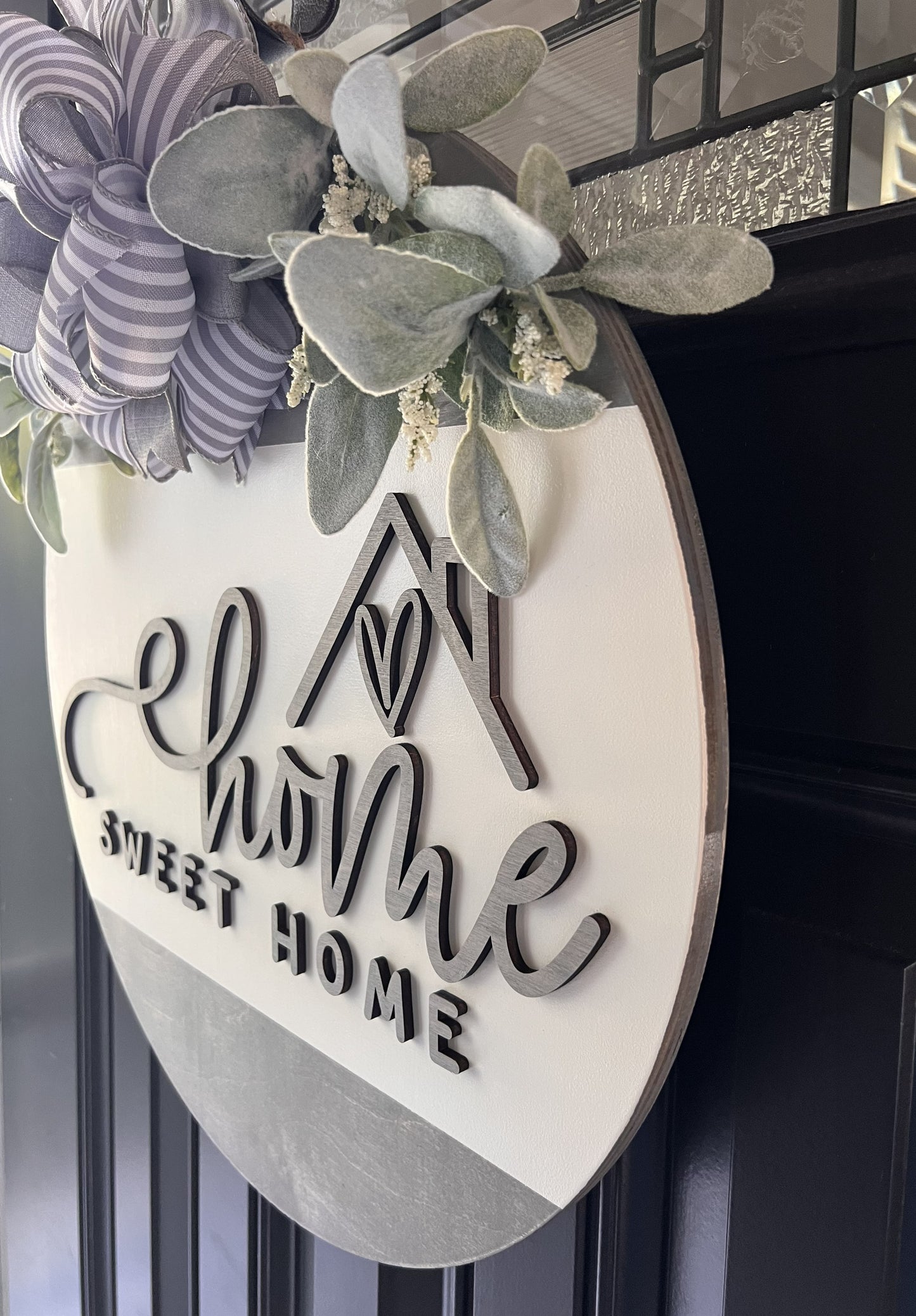 “Home Sweet Home wooden door hanger with neutral tones, layered lettering, bow and greenery on front door