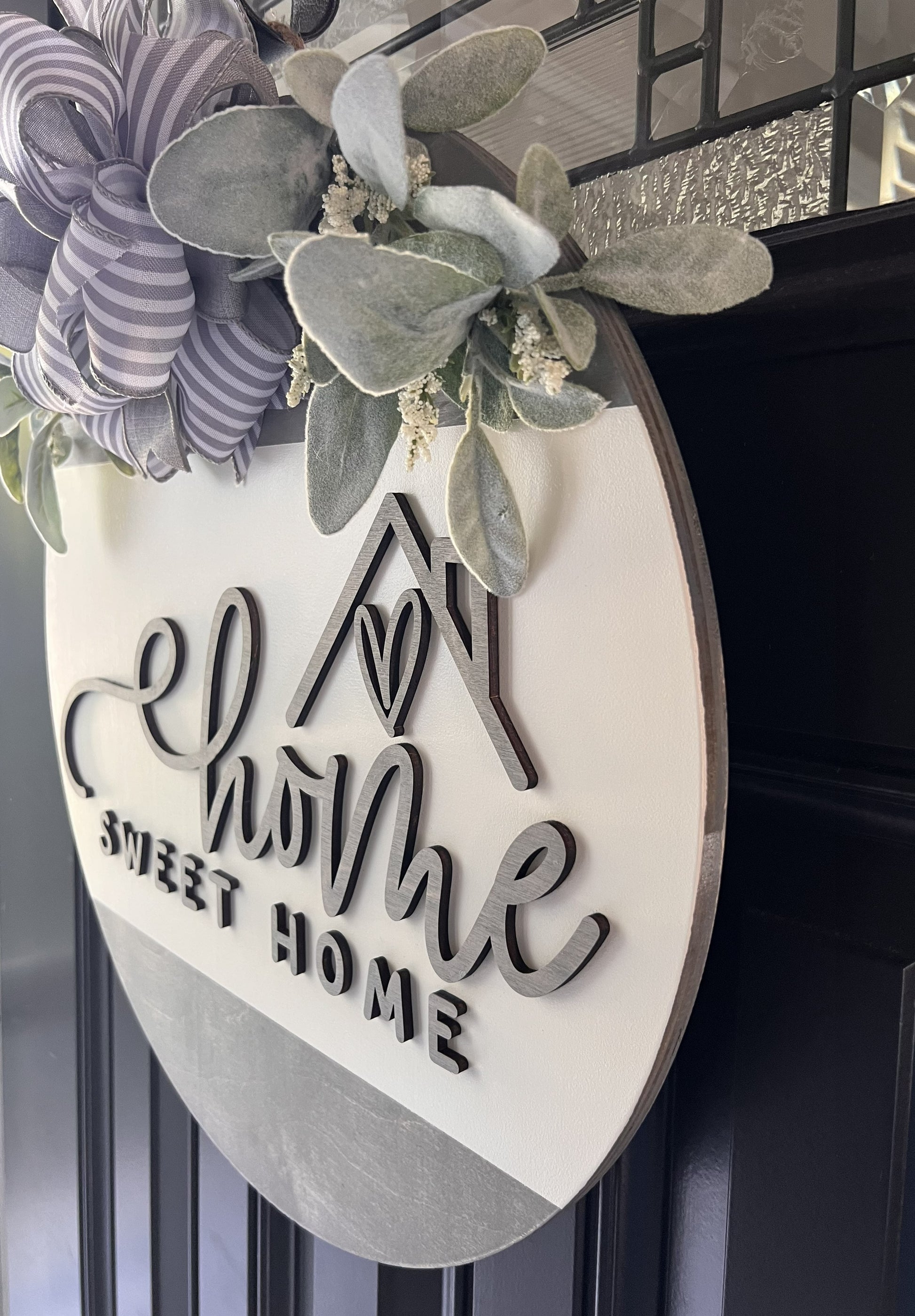 “Home Sweet Home wooden door hanger with neutral tones, layered lettering, bow and greenery on front door