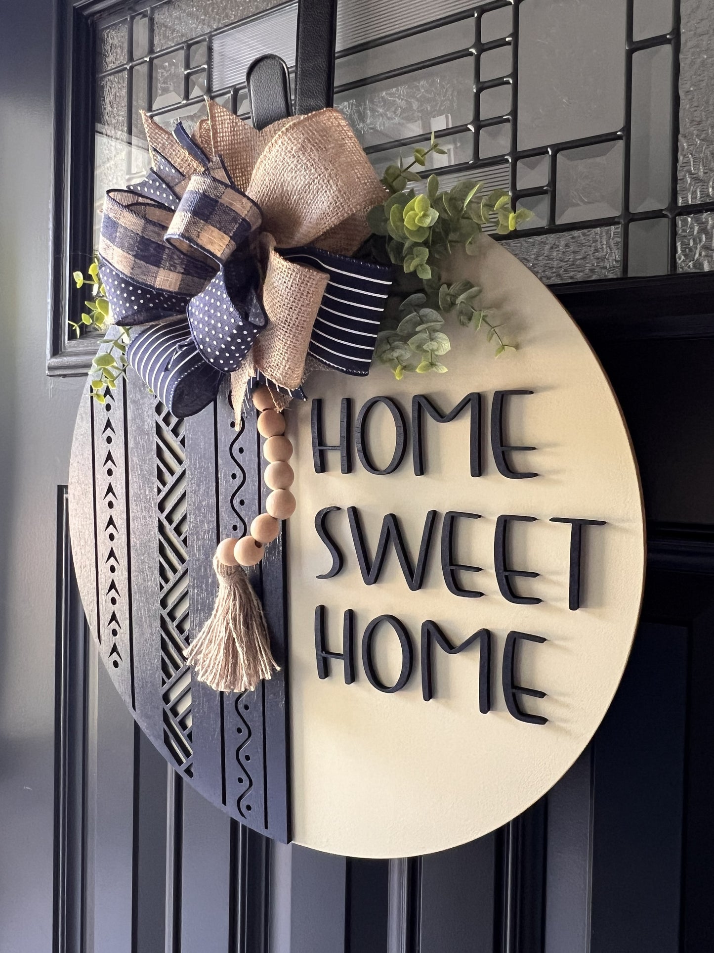 Decorative sign with 'Home Sweet Home' text with bow, greenery, and beaded tassel.  